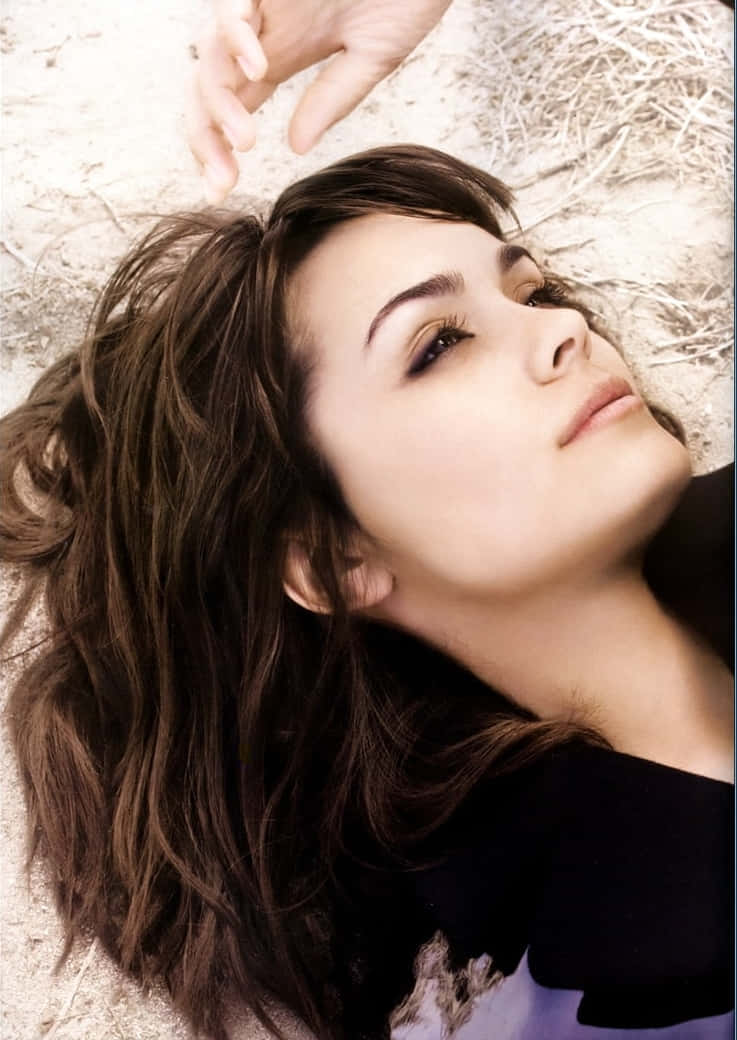Shannyn Sossamon 桌布 壁紙 — 一位棕色頭髮的女性躺在乾草上，向上凝視，一隻手懸浮在她的頭頂上方。