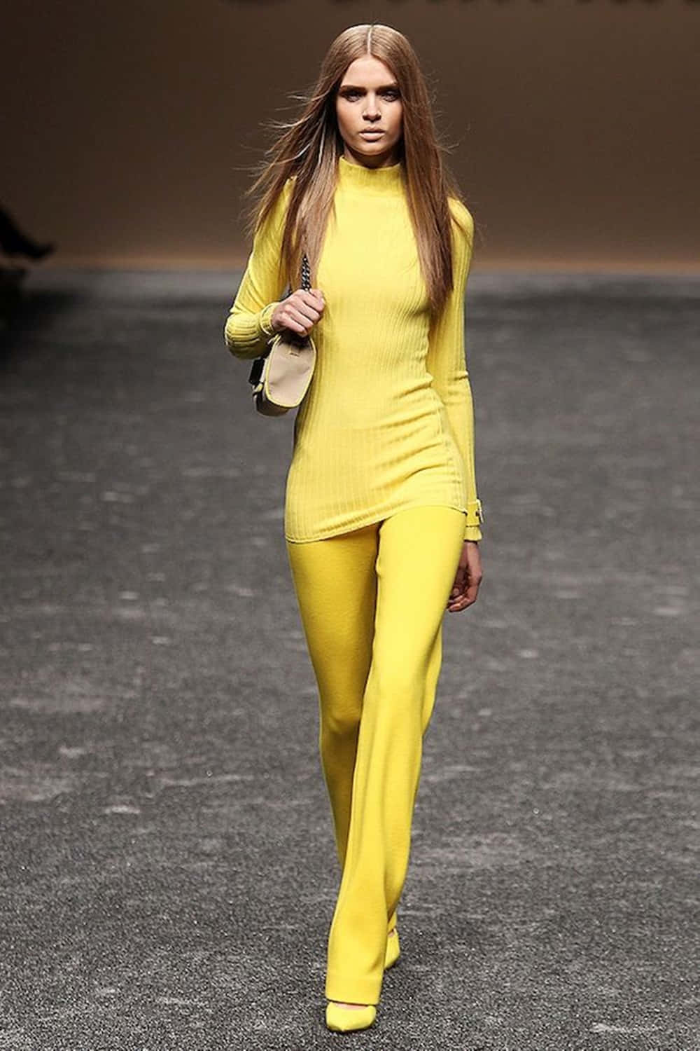 Yellow Fashion 桌布 壁紙 — 一位模特兒自信地走在天橋上，身穿大膽的黃色羅紋高領毛衣和相配的闊腿褲。