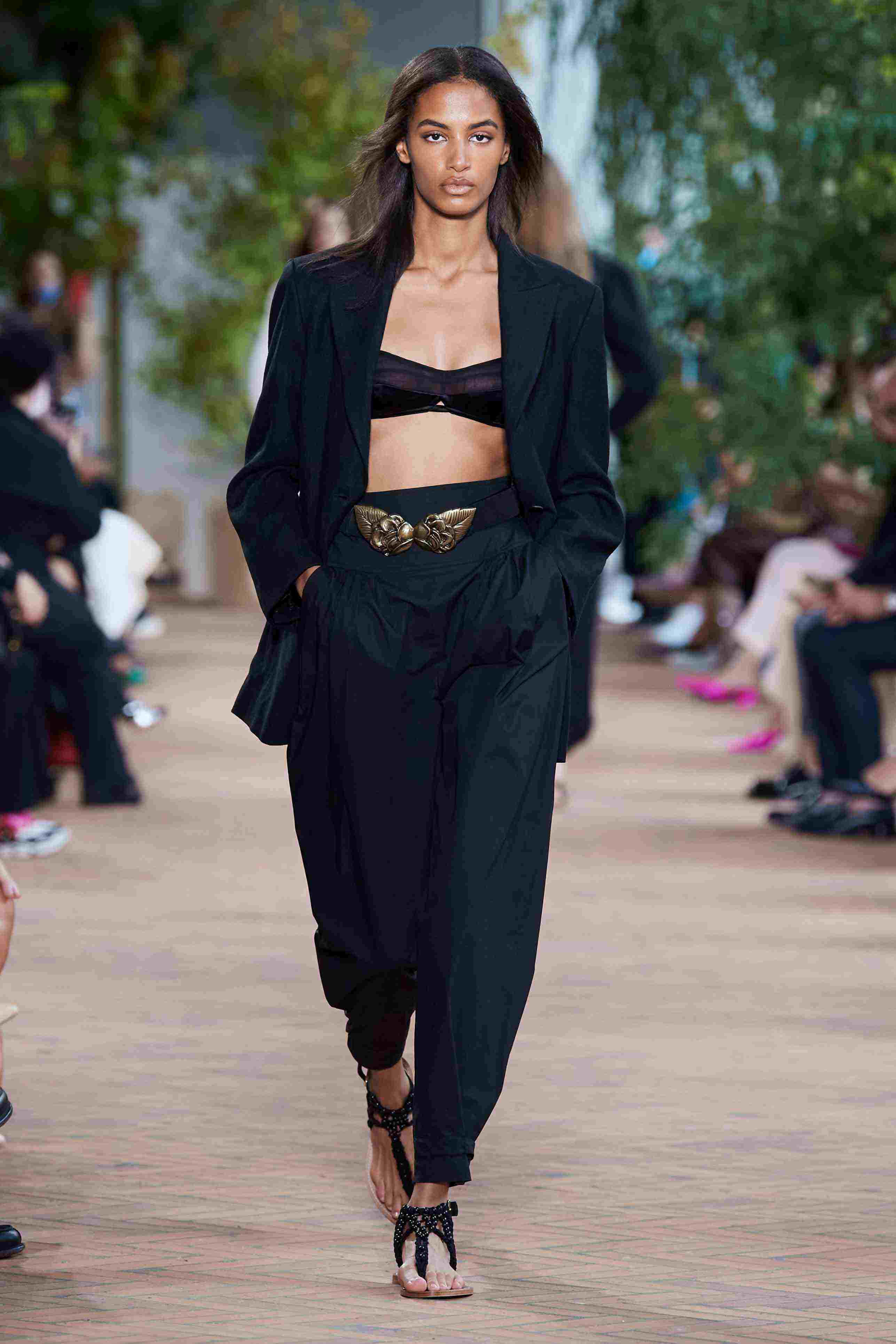 Minimalist Fashion 桌布 壁紙 — 一位模特兒自信地走在天橋上，身穿黑色西裝外套短上衣和闊腳褲，配以金色腰帶點綴。