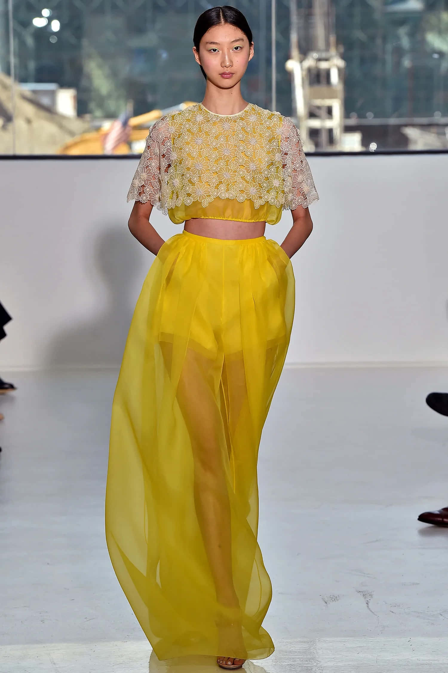 Yellow Fashion 桌布 壁紙 — 一位模特兒自信地走在天橋上，身穿鮮黃色蕾絲短身上衣和飄逸的薄紗裙。