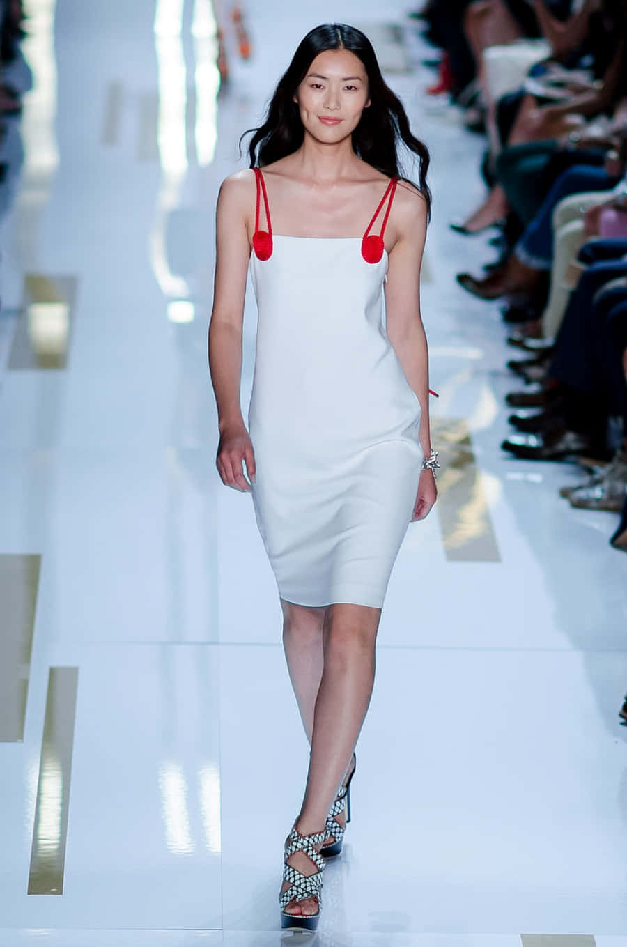 Fashion 桌布 壁紙 — 一位模特兒自信地走在明亮的白色天橋上，身穿簡約白色連衣裙，配以大膽的紅色肩帶和圖案高跟鞋。