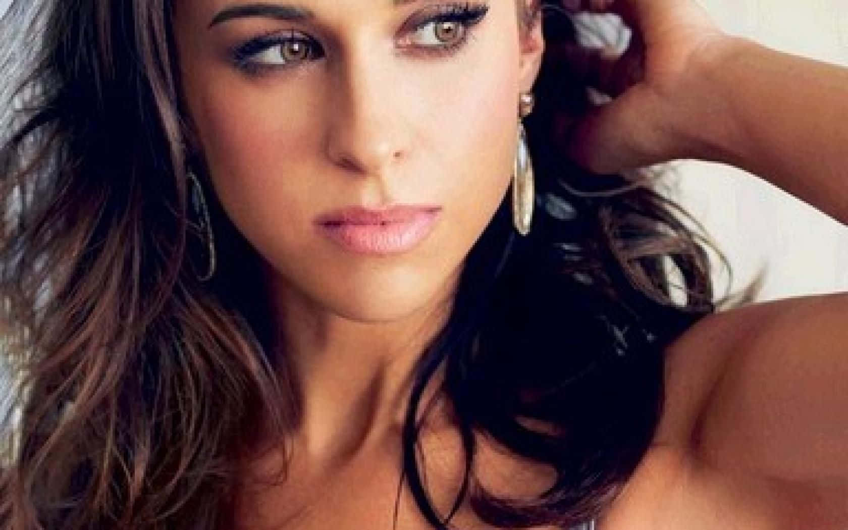 lacey chabert 桌布 壁紙 — 一位深色波浪長髮、雙目有神的女性特寫肖像，她若有所思地凝視著，同時輕撫自己的頭髮。