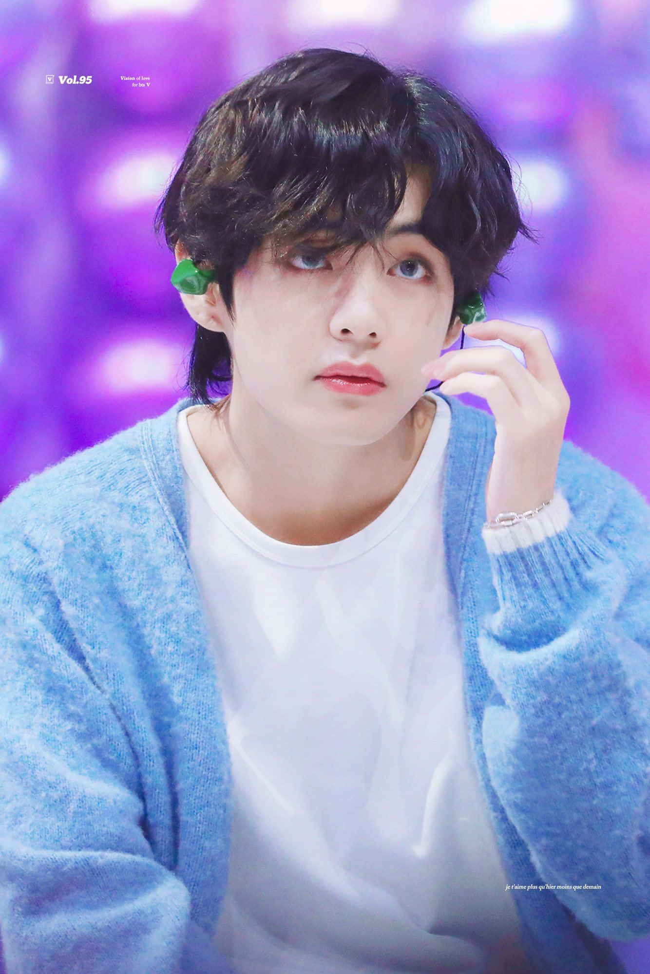 Taehyung Cute 桌布 壁紙 — 一位深色頭髮、戴著綠色耳環的年輕男子，穿著藍色開襟衫，在充滿活力的紫色背景下若有所思地凝視著。