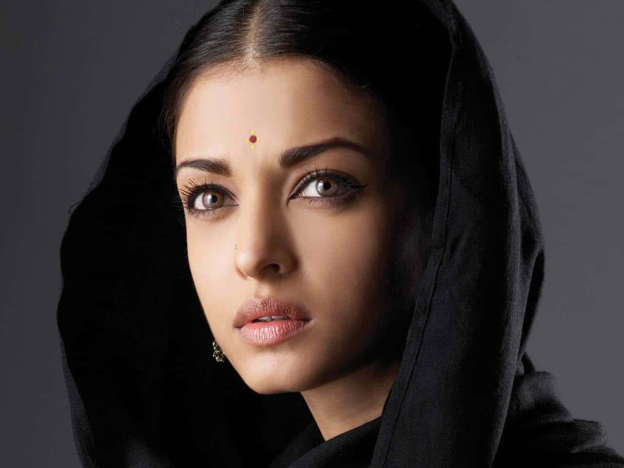 Aishwarya Rai 桌布 壁紙 — 一位深色頭髮、戴黑色頭巾的女性在灰色背景下凝視著相機。