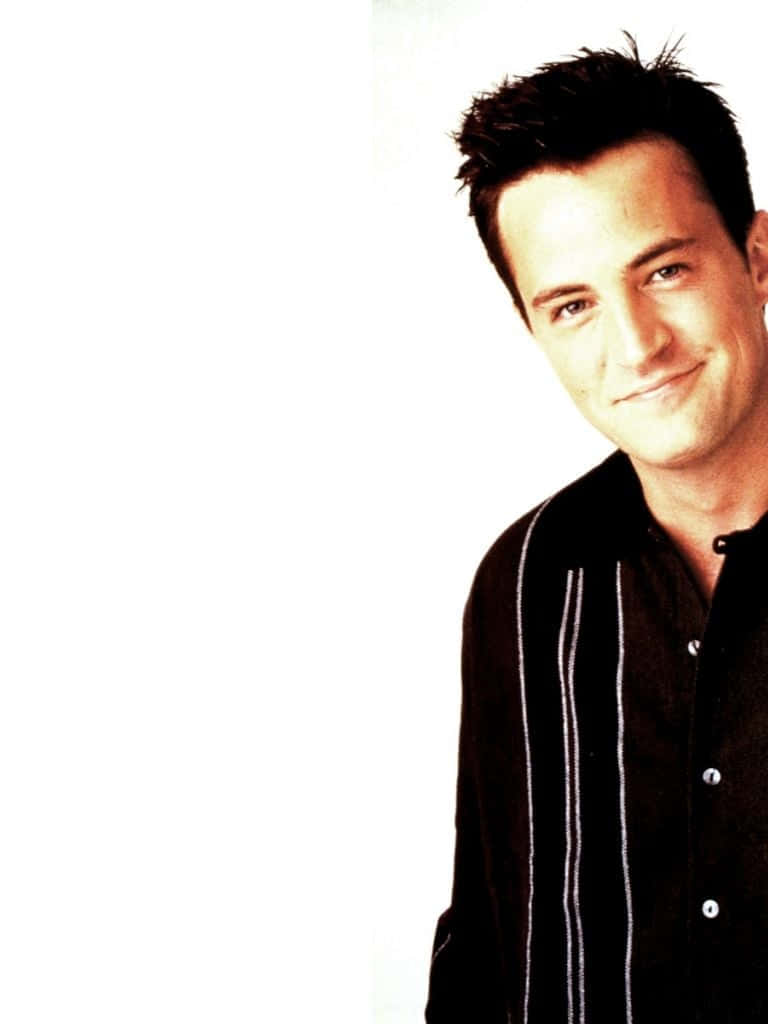 matthew perry 桌布 壁紙 — 一位深色頭髮、笑容溫暖的男子，穿著一件帶有白色垂直條紋的黑色襯衫，背景是純白色。