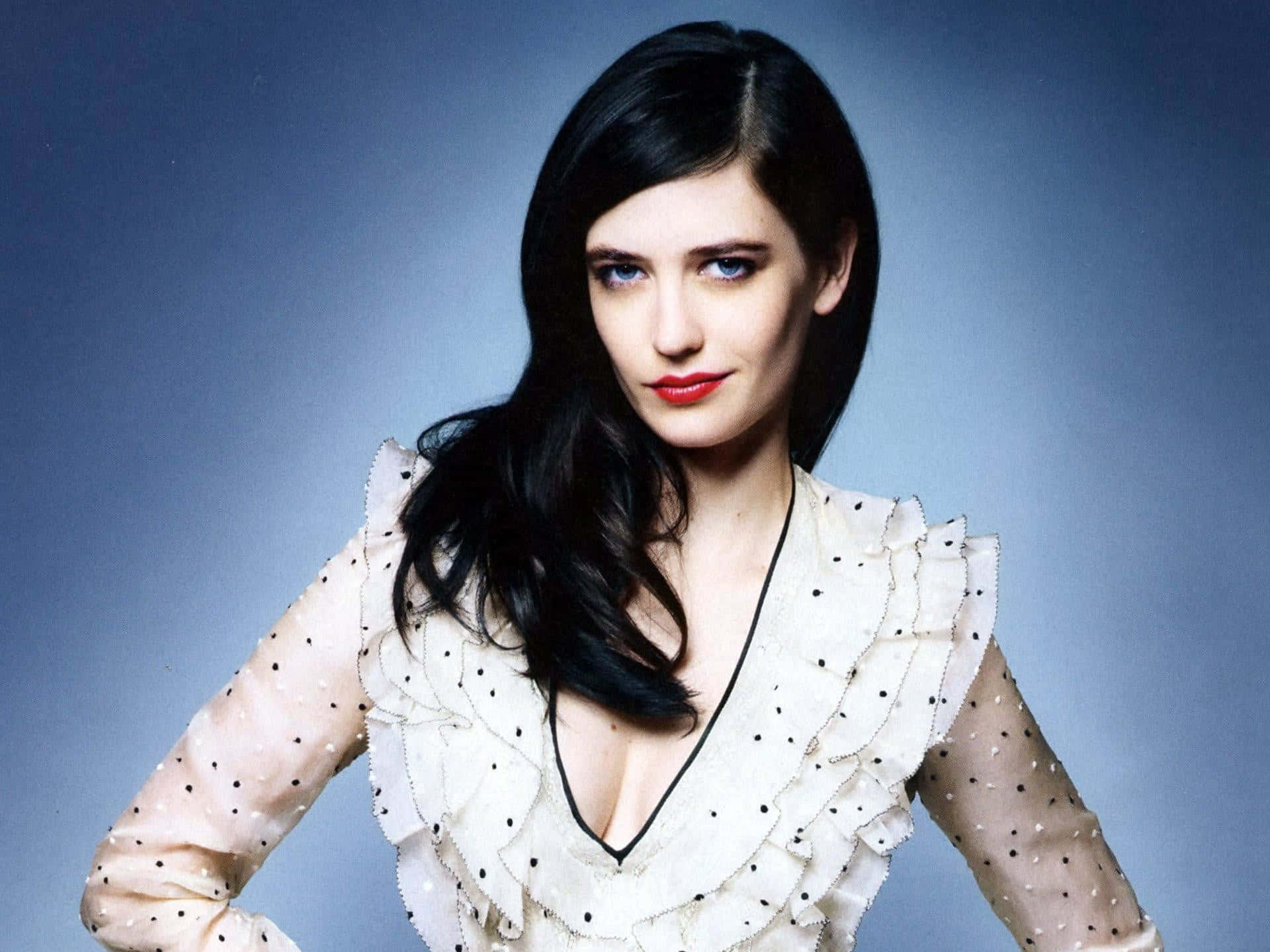 eva green 桌布 壁紙 — 一位深色頭髮、紅唇的女性，在漸變藍色背景前穿著波點荷葉邊上衣。