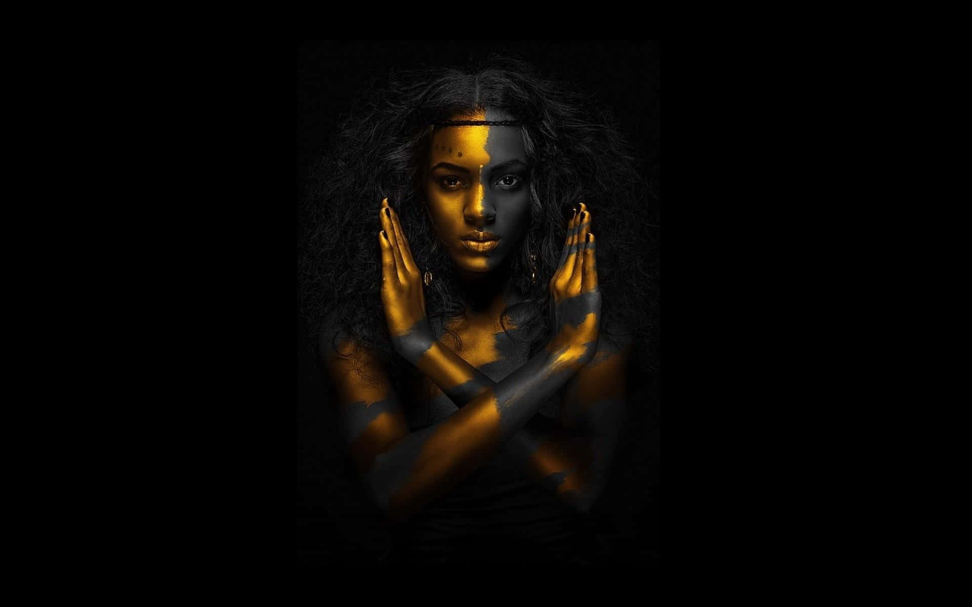 Black Is Beautiful 桌布 壁紙 — 一位深色頭髮、臉部一半金色一半黑色的女性，雙手交叉放在胸前，在黑色背景前凝視前方。