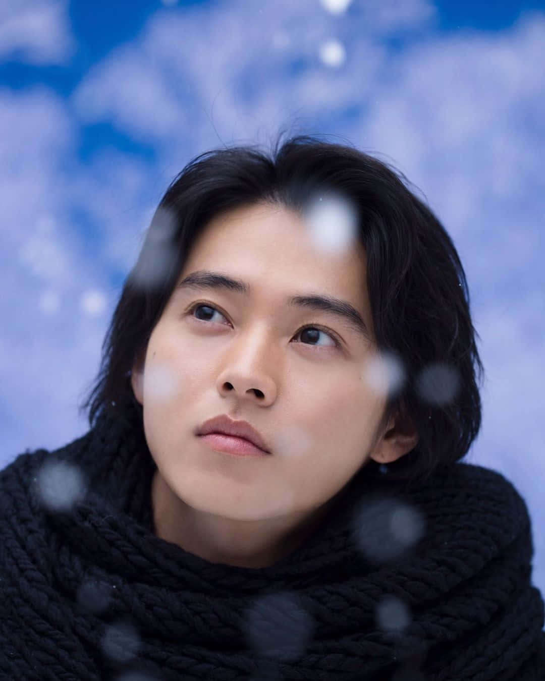 Japanese 桌布 壁紙 — 一位深色頭髮的年輕男子透過積雪的窗戶仰望柔和的藍天。