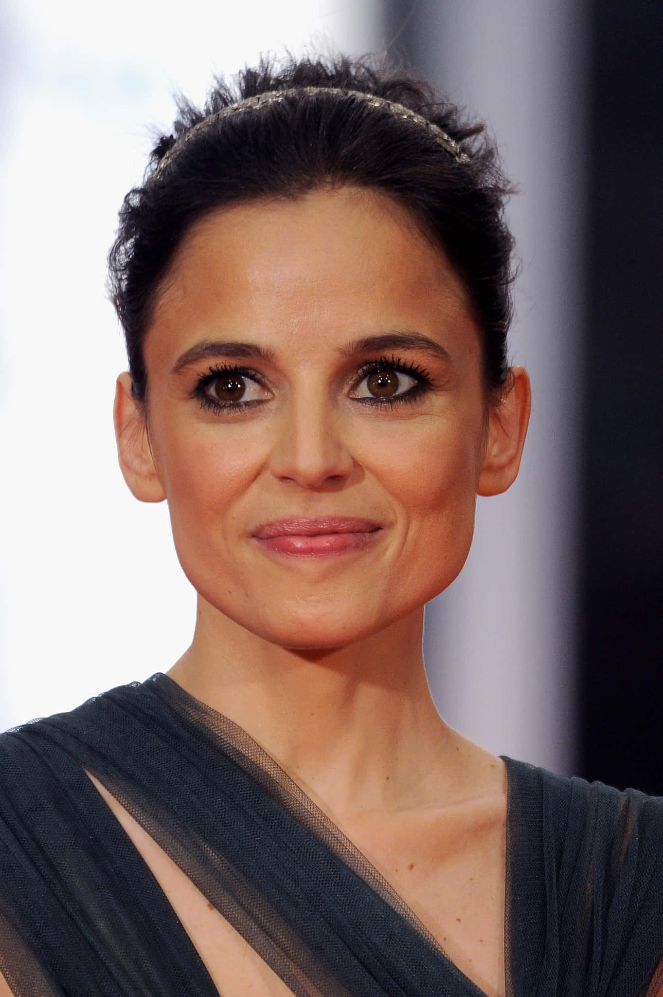 Elena Anaya 桌布 壁紙 — 一位深色頭髮盤起、戴著精緻頭帶和深色垂墜連衣裙的女子的特寫肖像。