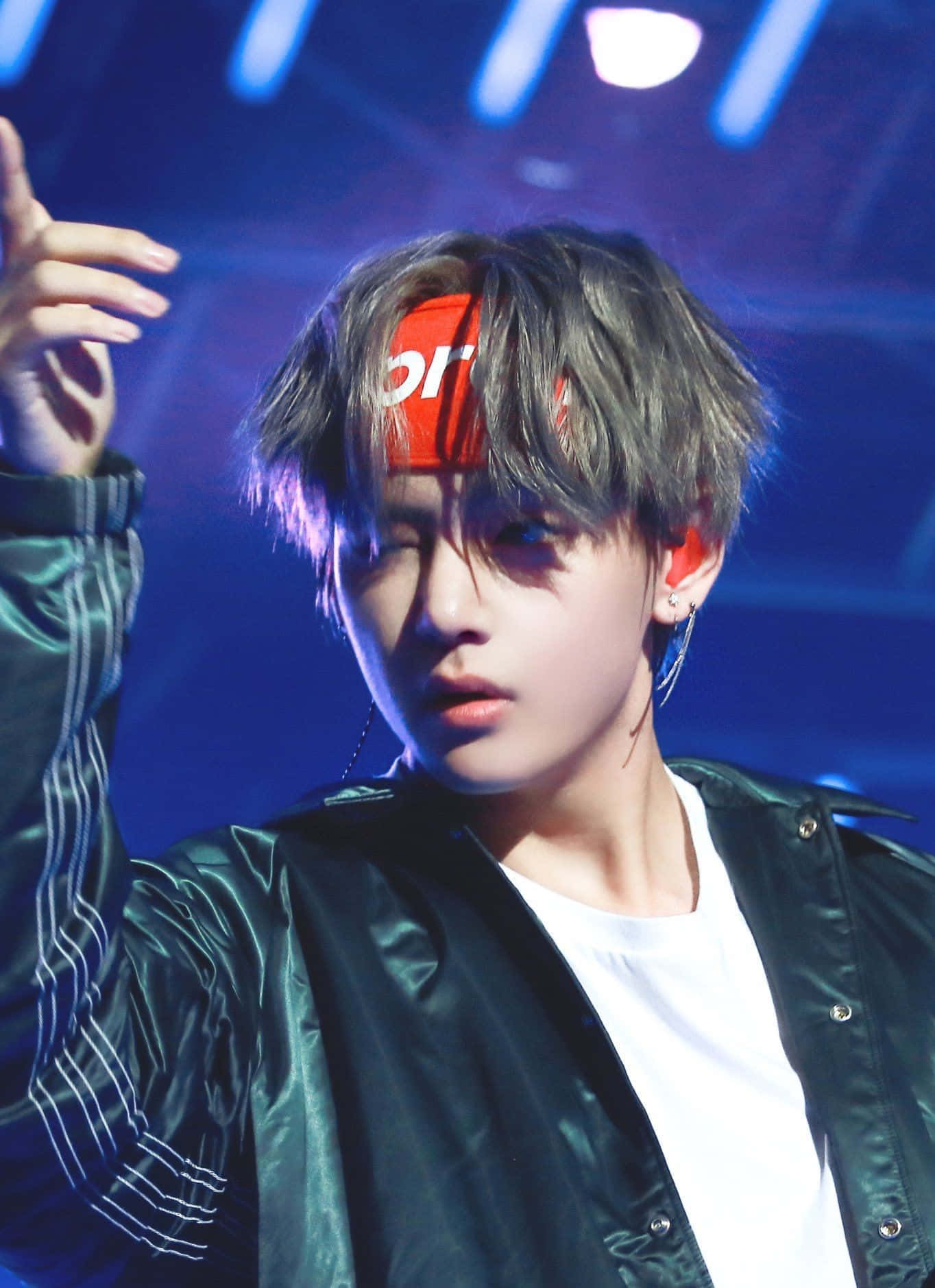 Bts Live 桌布 壁紙 — 一位灰髮、戴紅色頭帶的年輕男子，在藍色舞台燈光下穿著閃亮的綠色外套表演。