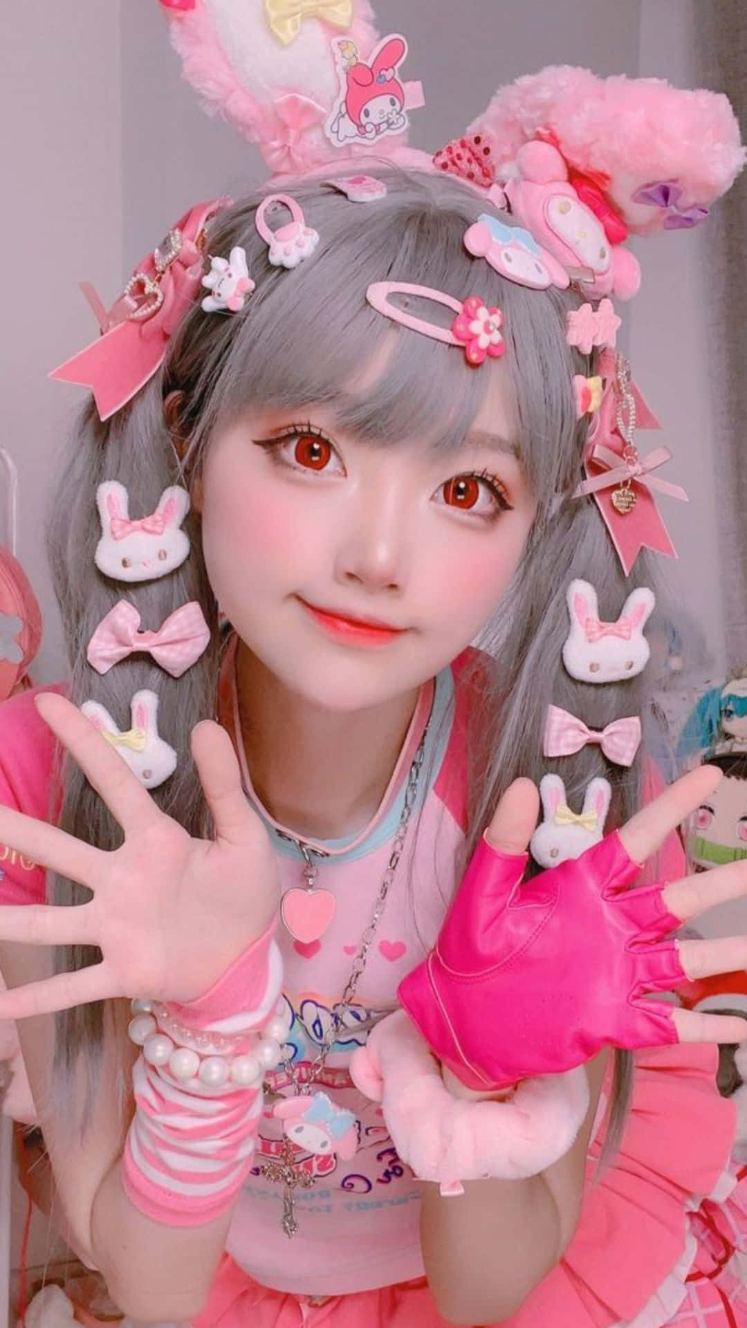 Cosplay Anime Kawaii 桌布 壁紙 — 一位灰髮年輕女性戴著粉紅色飾物，穿著帶有兔子圖案和柔和色彩的卡哇伊服裝，開心地擺姿勢。