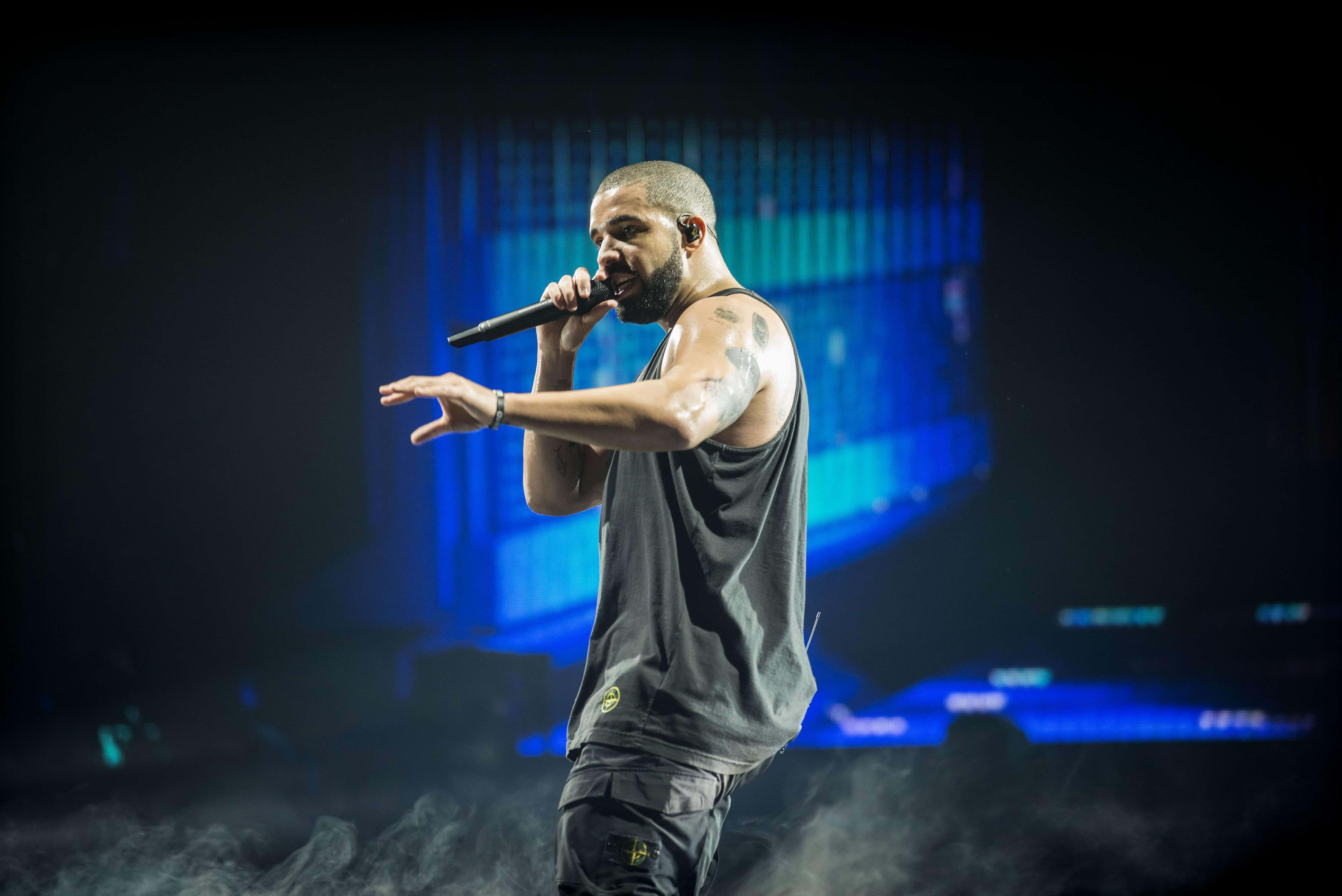 Drake 桌布 壁紙 — 一位男歌手在藍色燈光下表演，煙霧在他腳邊旋轉。