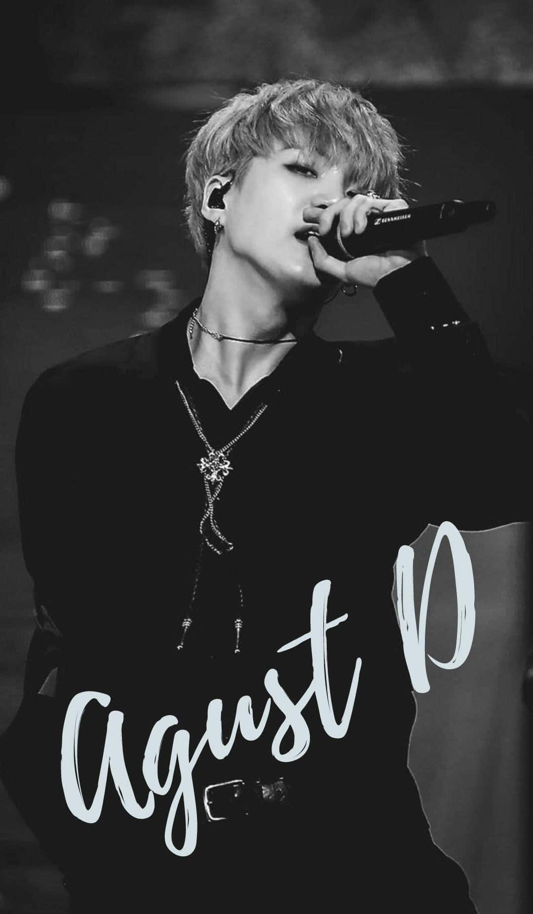 Agust D 桌布 壁紙 — 一位男歌手深情演唱的黑白特寫，頭髮造型時尚，佩戴多層項鍊。