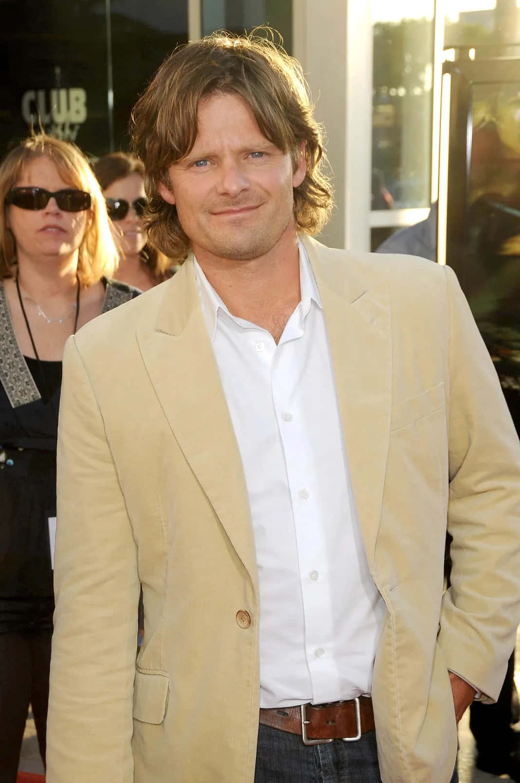 Steve Zahn 桌布 壁紙 — 一位留著及肩棕色頭髮的男子，穿著米色西裝外套和白色襯衫，在戶外活動中溫暖地微笑。