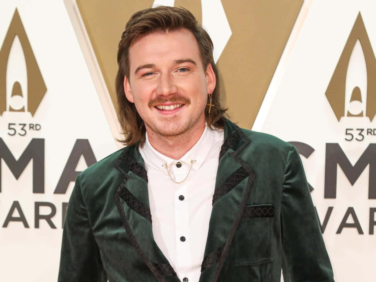 Morgan Wallen 桌布 壁紙 — 一位留著鬍鬚和長髮的微笑男士，在第53屆ACM頒獎典禮紅毯上穿著綠色天鵝絨西裝外套。