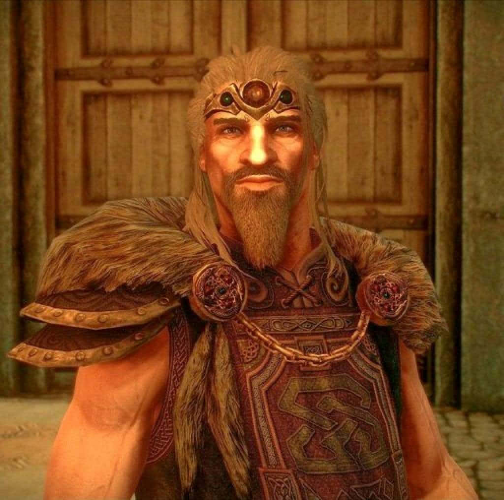Jarl Balgruuf 桌布 壁紙 — 一位留著鬍鬚的奇幻戰士，戴著鑲有寶石的頭帶，身穿毛皮襯裡的盔甲，站在一扇木門前。