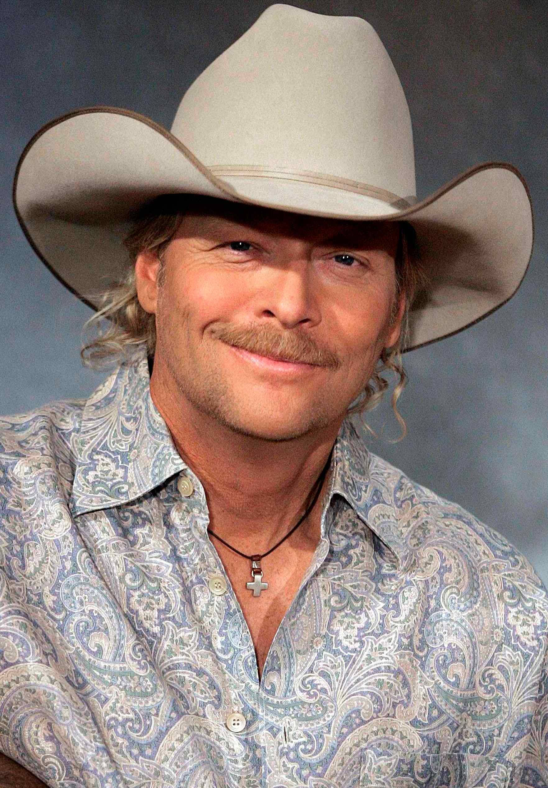 Alan Jackson 桌布 壁紙 — 一位留鬍子、戴牛仔帽、穿著佩斯利襯衫的男子在灰色攝影棚背景前微笑。