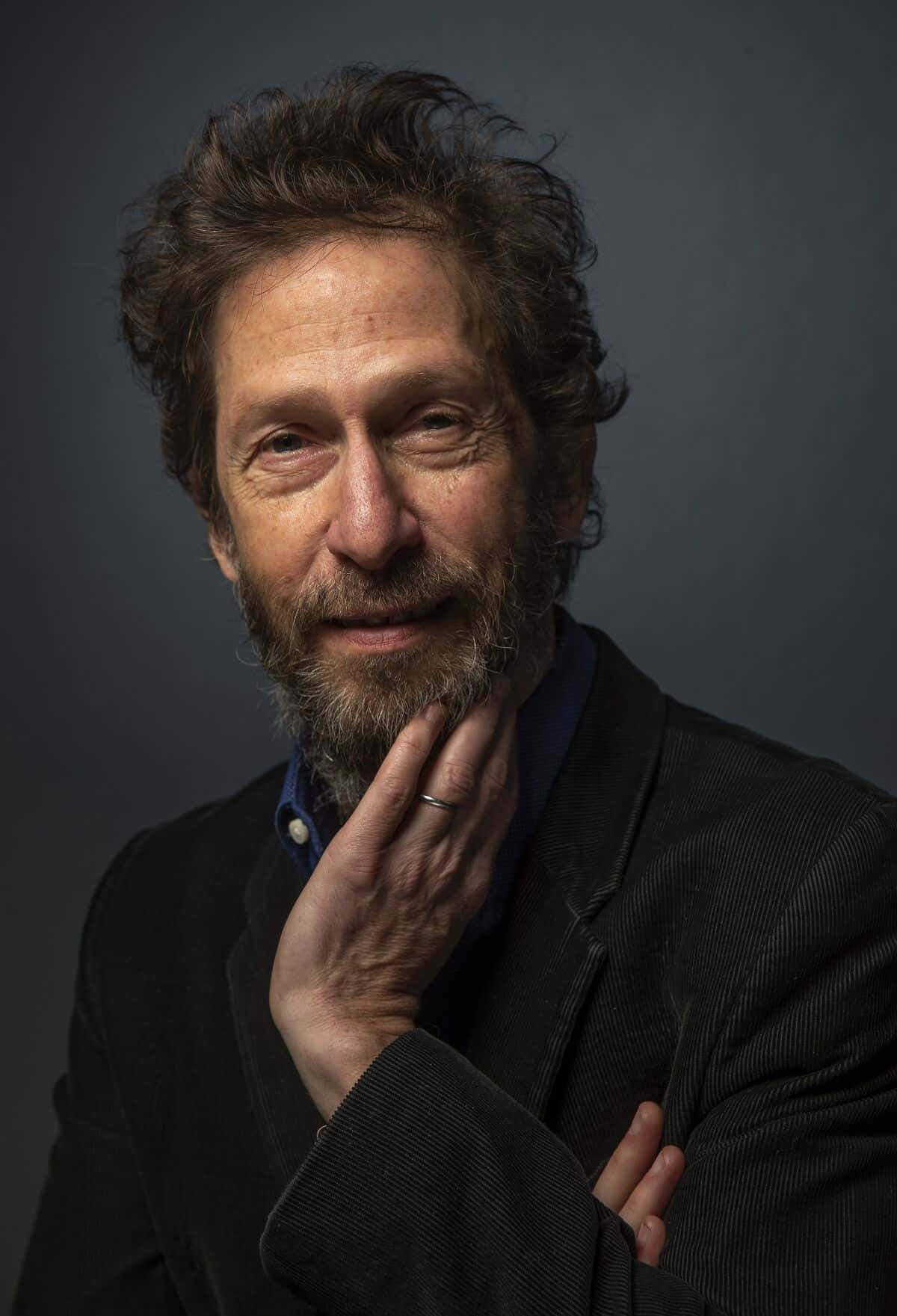 Tim Blake Nelson 桌布 壁紙 — 一位留鬍子、頭髮凌亂、若有所思的中年男子，在深灰色工作室背景下輕輕觸碰下巴。