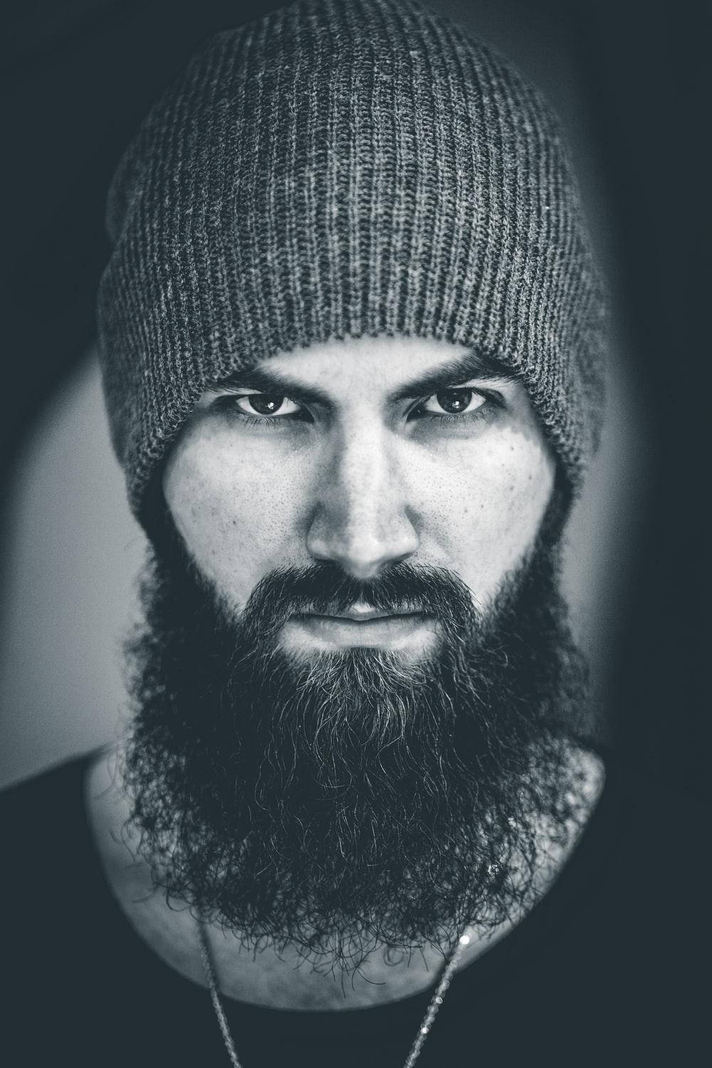 beard 桌布 壁紙 — 一位留鬍鬚、眼神銳利的男士戴著針織冷帽的黑白肖像。