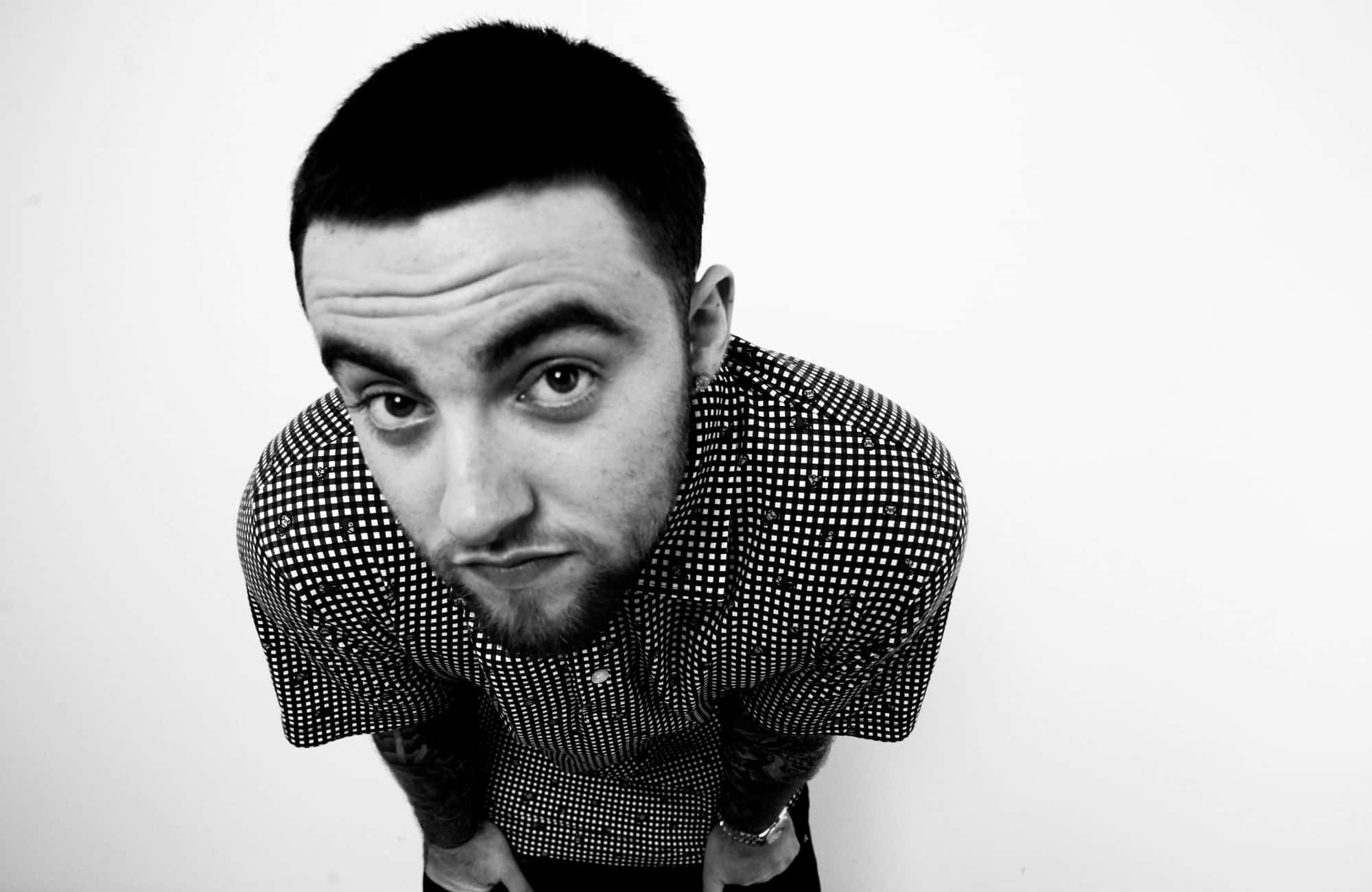 Mac Miller 桌布 壁紙 — 一位留鬍鬚、身穿圖案襯衫的男子，在純白背景前以黑白風格強烈前傾。