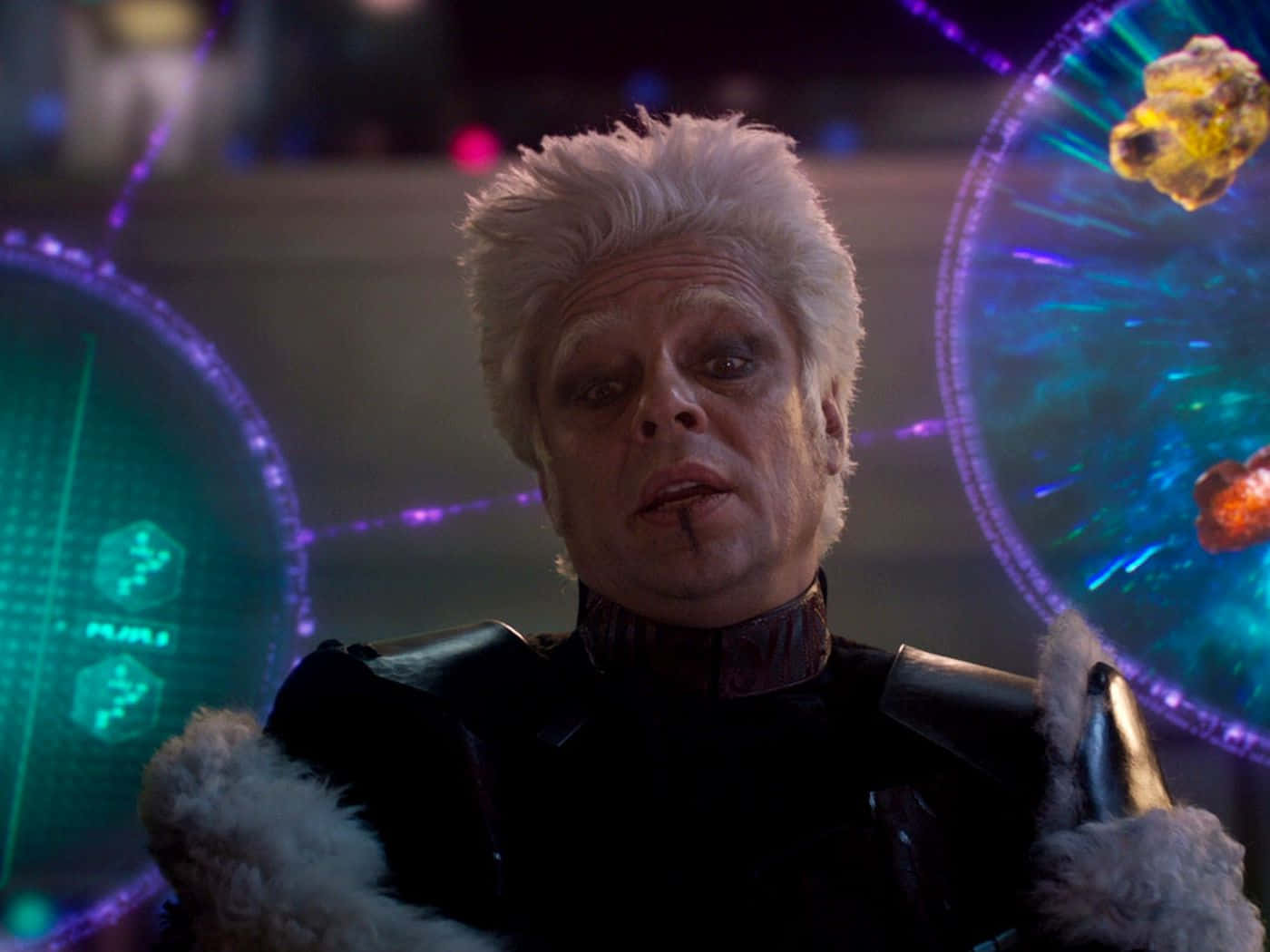 Mind Stone 桌布 壁紙 — 一位白髮、深色妝容的男子在科幻控制室中，對著發光的全息屏幕凝視。