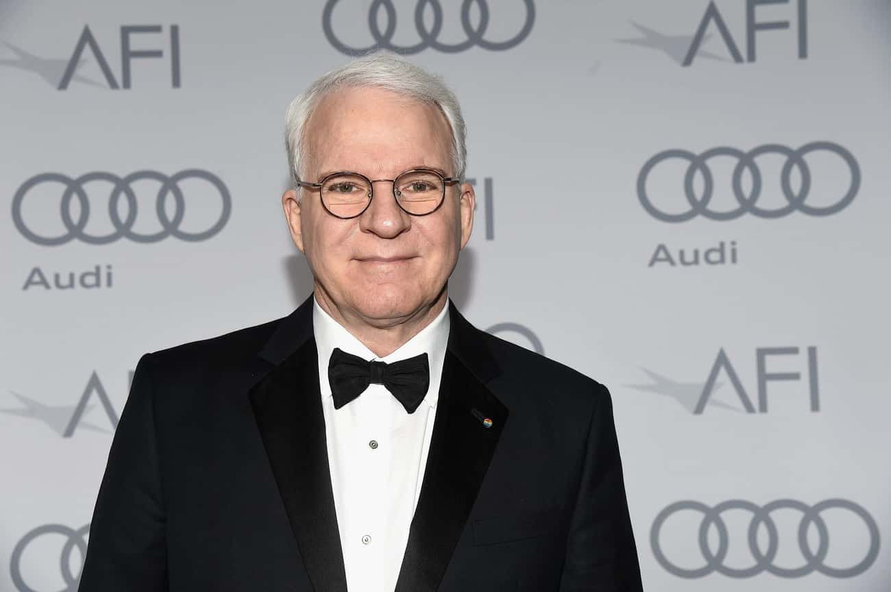steve martin 桌布 壁紙 — 一位白髮戴眼鏡的男子，身穿黑色燕尾服和領結，背景是重複的AFI和Audi標誌。