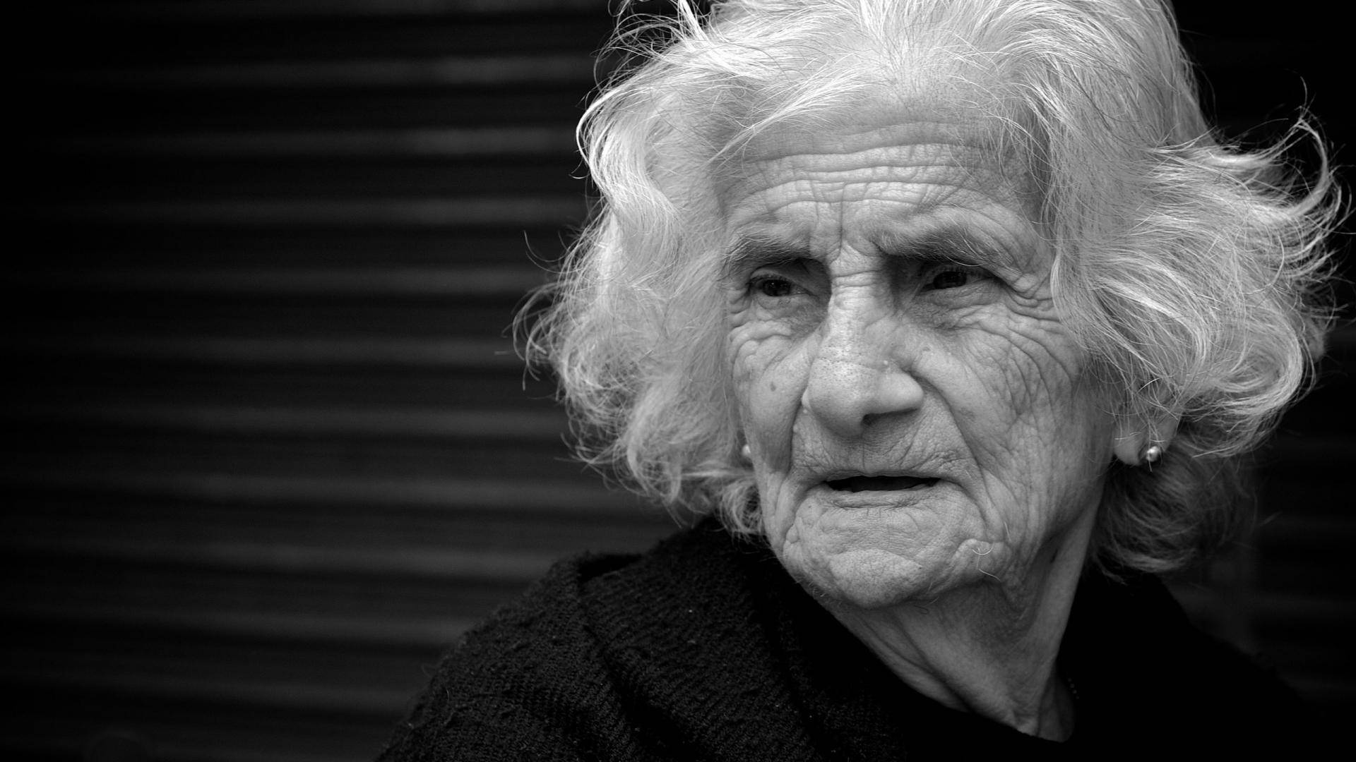 Grandma 桌布 壁紙 — 一位白髮蒼蒼、滿臉皺紋的老婦人的黑白特寫肖像，若有所思地凝視著。