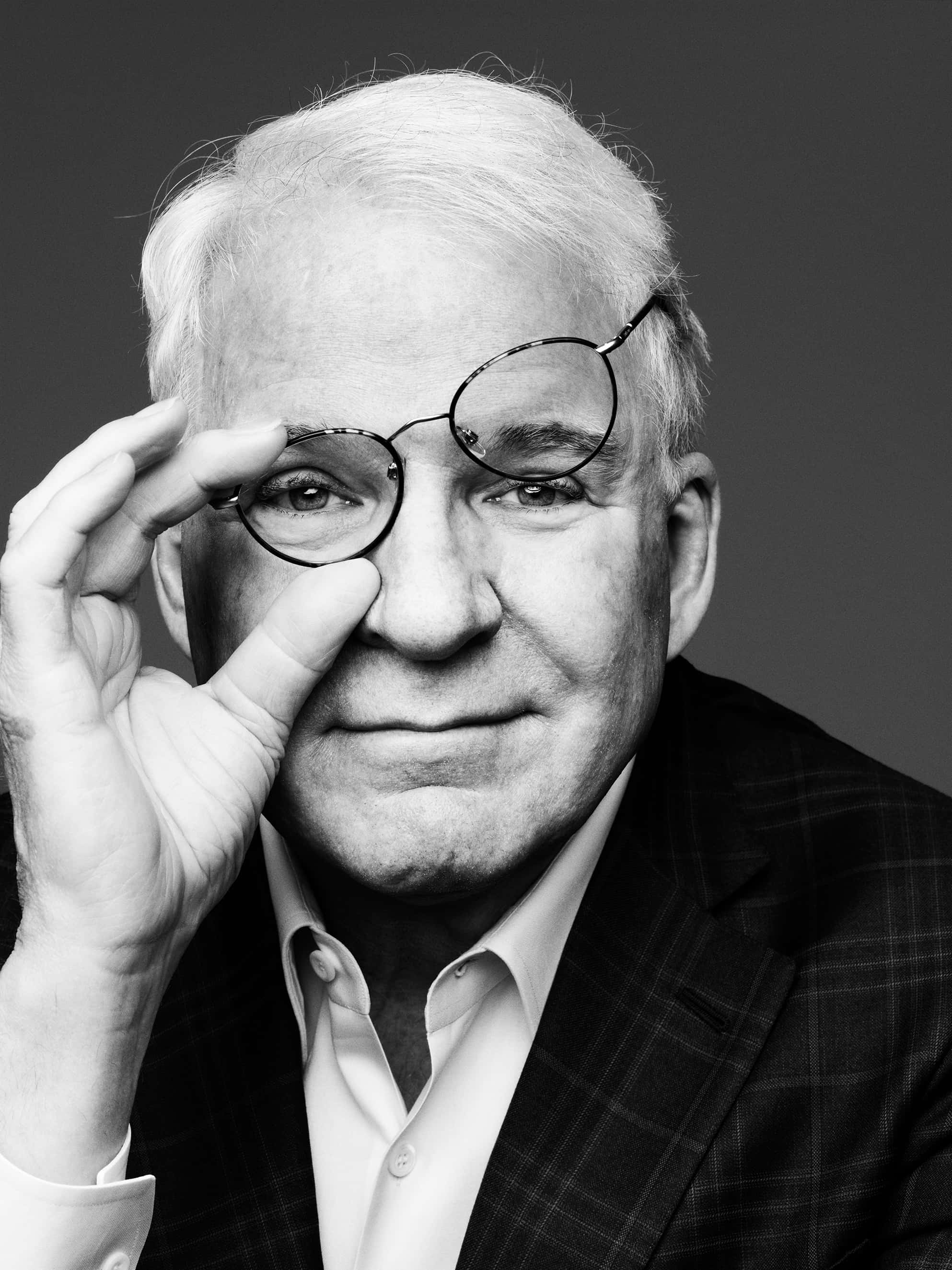 steve martin 桌布 壁紙 — 一位白髮長者調整圓框眼鏡的黑白肖像，表情若有所思。