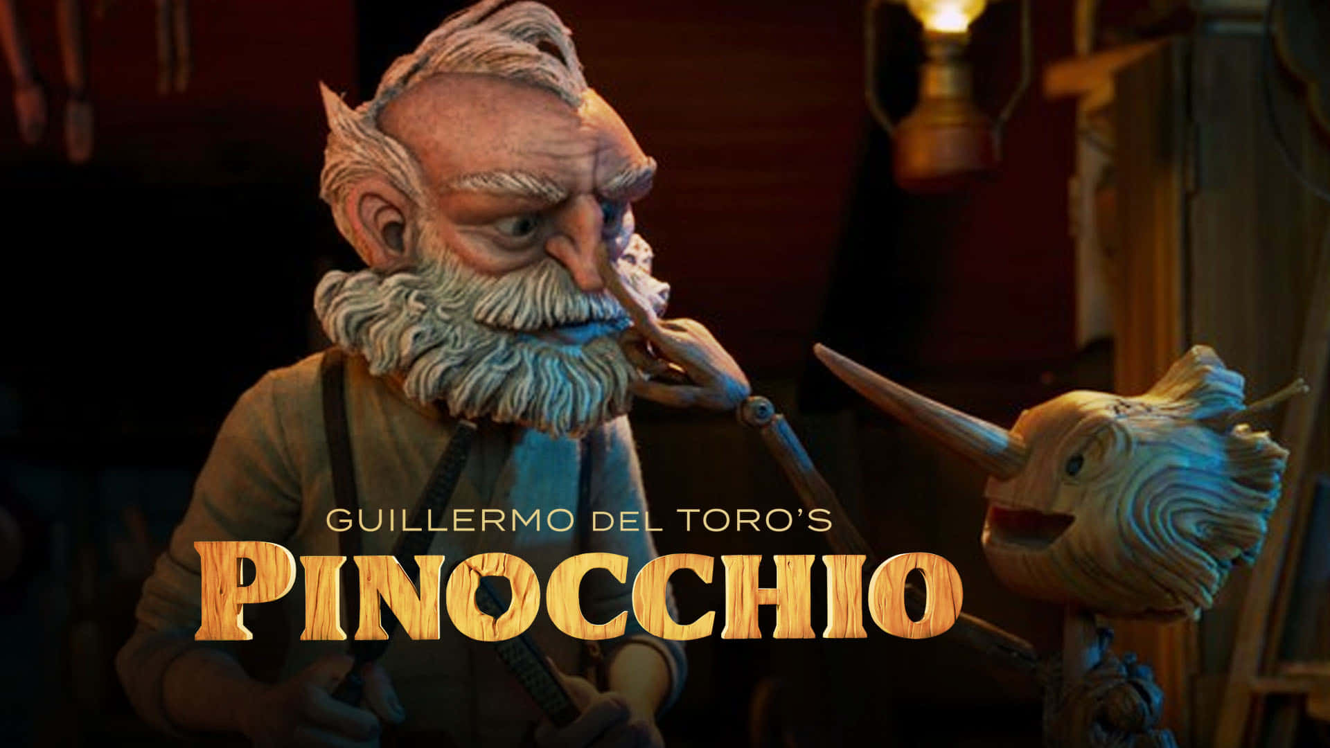 Guillermo Del Toro's Pinocchio 桌布 壁紙 — 一位白鬍子的灰髮木雕師傅在光線昏暗的工作室裡拿著一個長鼻子的木偶。