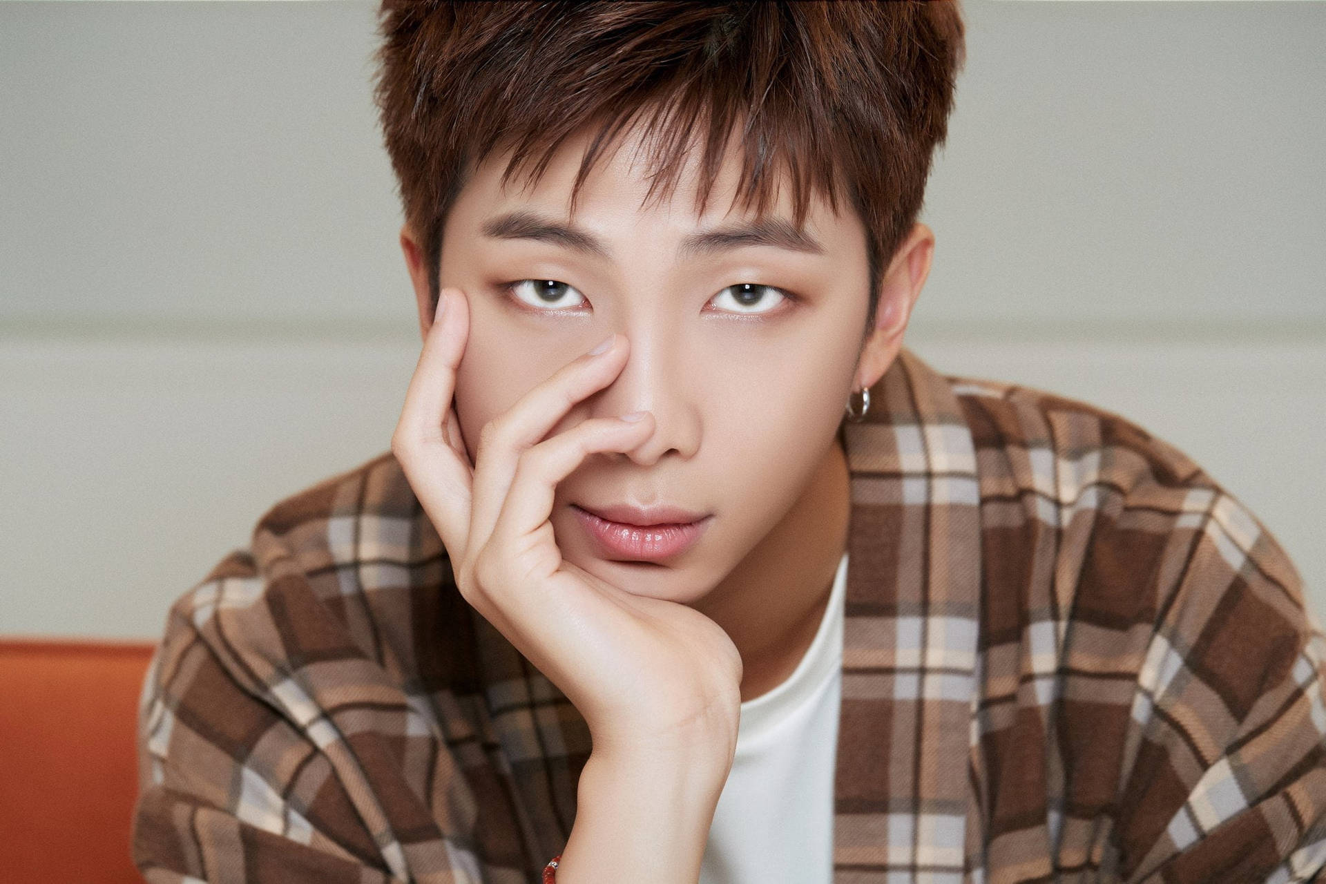 BTS《Life Goes On》RM 壁紙 — 一位短棕髮的年輕男子穿著格仔襯衫，托腮沉思地望著相機。
