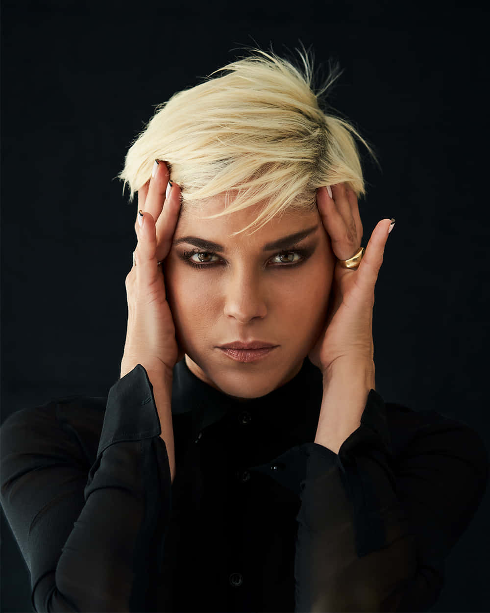 Selma Blair 桌布 壁紙 — 一位短白金髮、眼神強烈的女性，在黑色背景前用雙手抱住頭部。