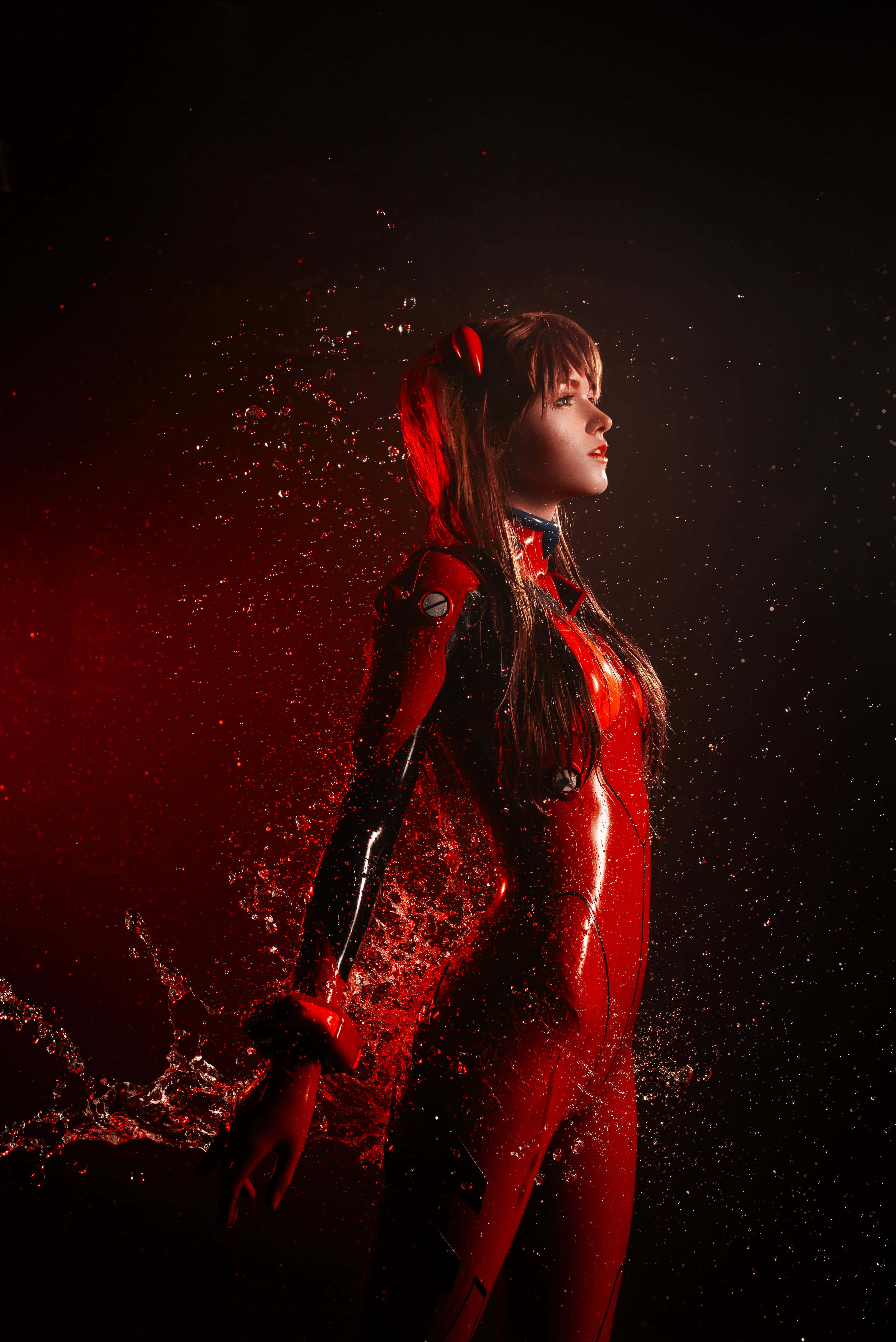 Gaming Cosplay 桌布 壁紙 — 一位穿著亮面紅黑Eva Unit-01服裝的角色扮演者，在黑暗背景下站在戲劇性的紅色水花中。