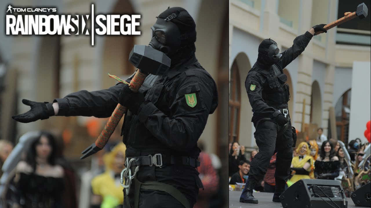 Rainbow Six Siege Sledge 桌布 壁紙 — 一位穿著全黑戰術裝備的角色扮演者在展會上動態地揮舞著一把大錘。