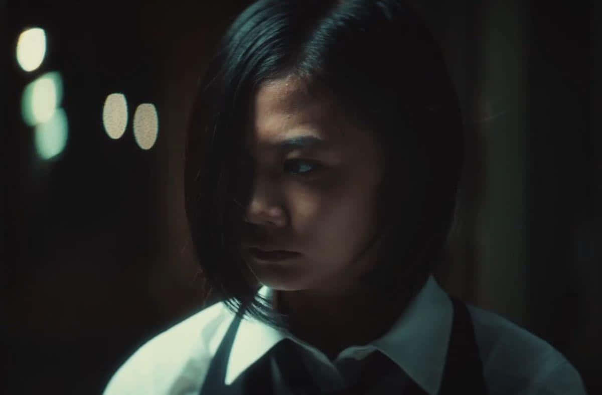 Tokyo Ghoul Movie 桌布 壁紙 — 一位穿著校服的年輕女子在光線昏暗、背景有柔和燈光的房間裡專注地凝視。