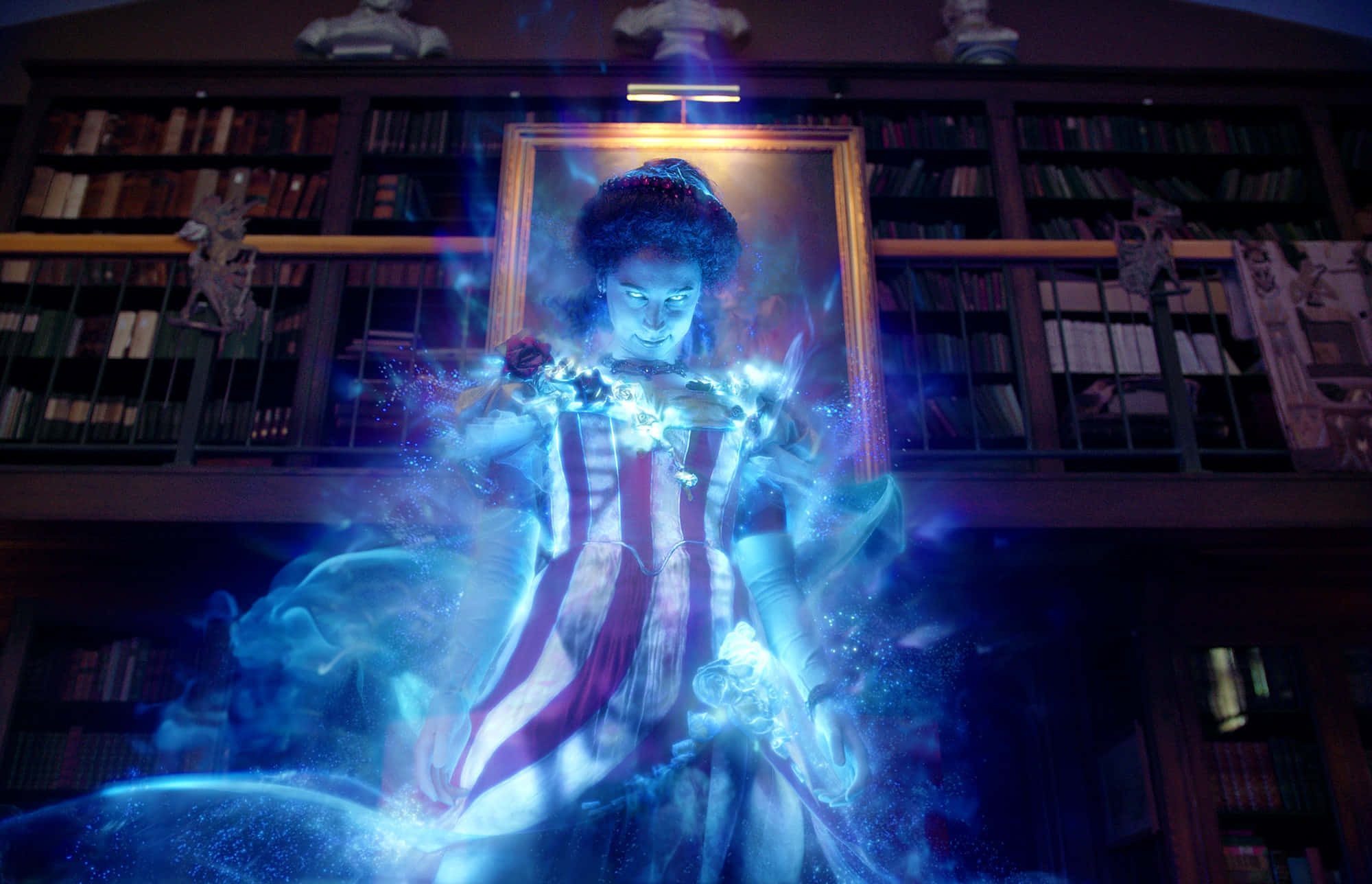 Ghostbusters 桌布 壁紙 — 一位穿著條紋連衣裙的發光女巫在一個充滿書架的宏偉圖書館中施展魔法。