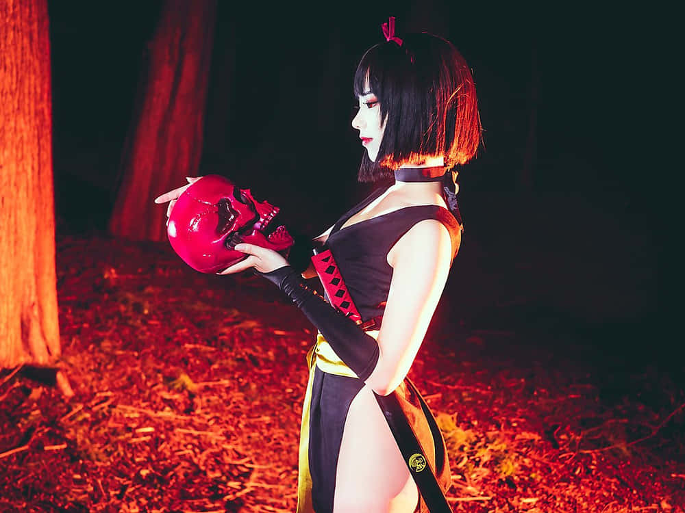 Inuyasha Yura 桌布 壁紙 — 一位穿著深色服裝的角色扮演者在夜間森林中，在溫暖的紅色燈光下拿著一個發光的紅色頭骨。