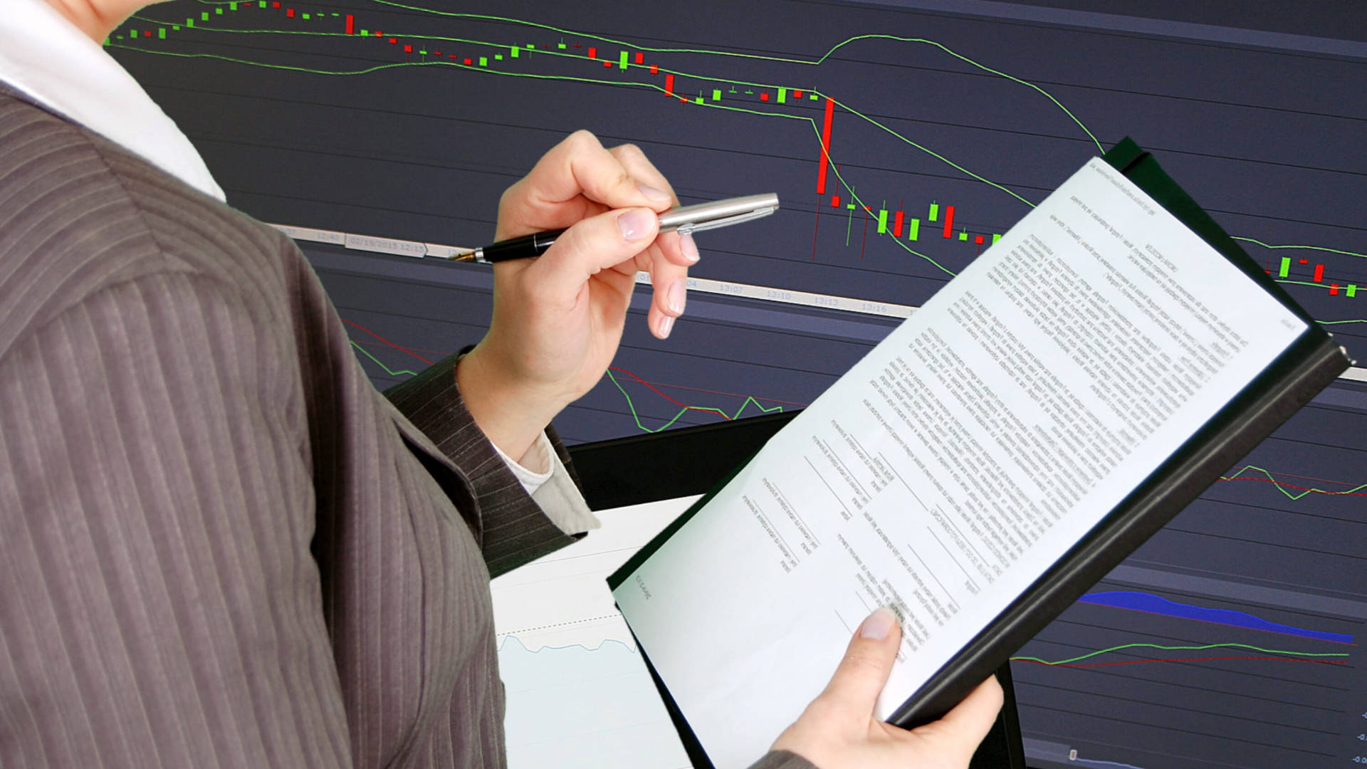 Business 桌布 壁紙 — 一位穿著細條紋西裝的交易員手持筆分析金融圖表和文件。