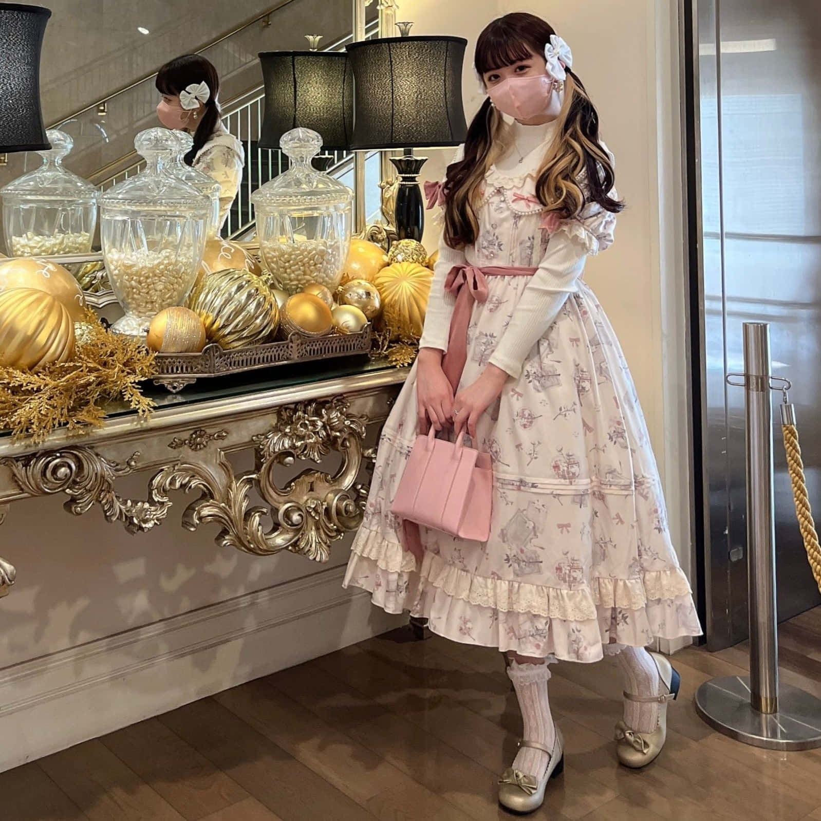 Lolita Fashion 桌布 壁紙 — 一位穿著花卉洛麗塔裙的年輕女子站在一張裝飾華麗的玄關桌旁，桌上擺放著金色南瓜和玻璃罐。