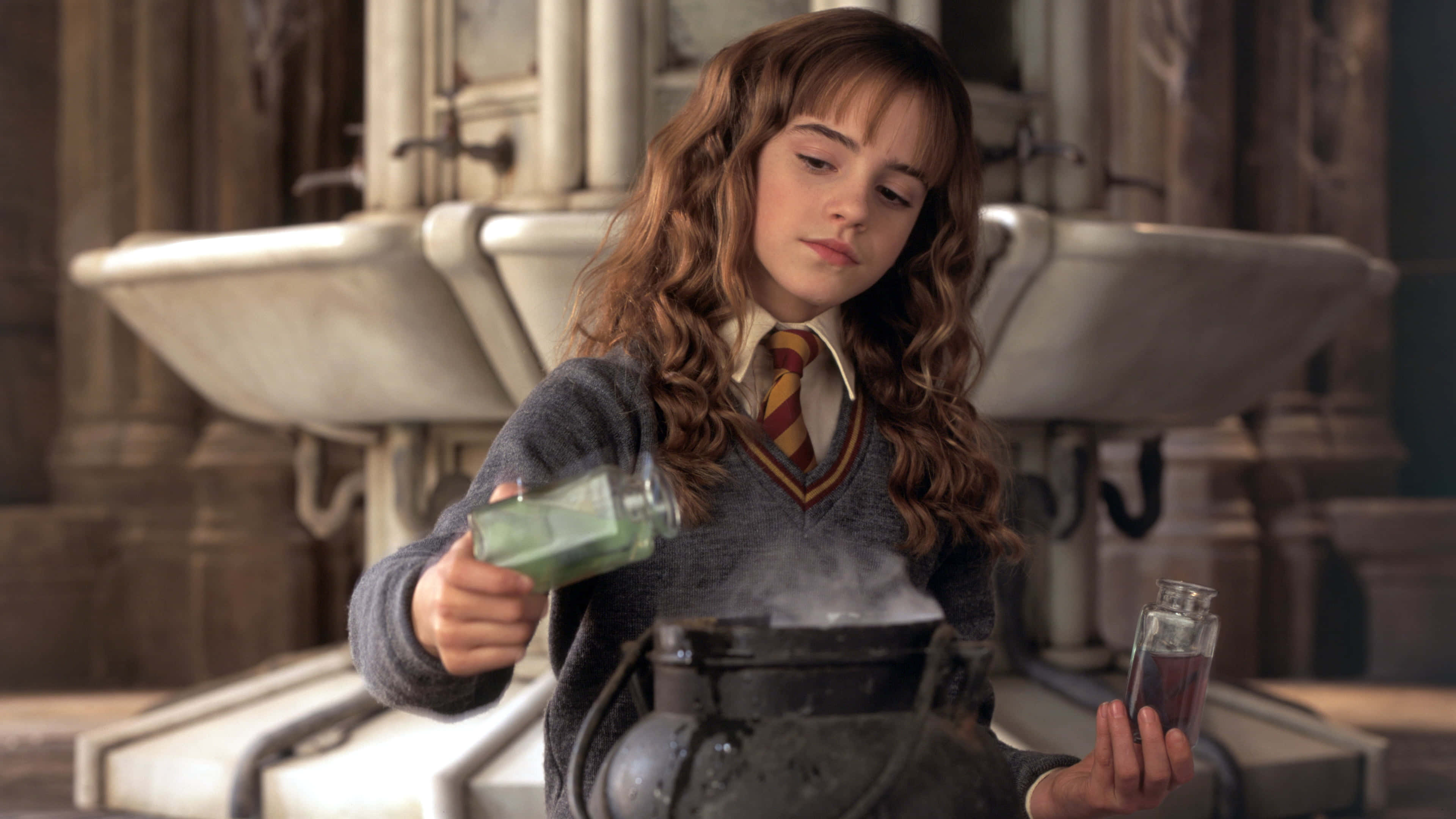 Harry Potter 4K 桌布 壁紙 — 一位穿著霍格華茲制服的小女巫，在石牆教室裡小心地將發光的綠色液體倒入冒煙的大鍋中。