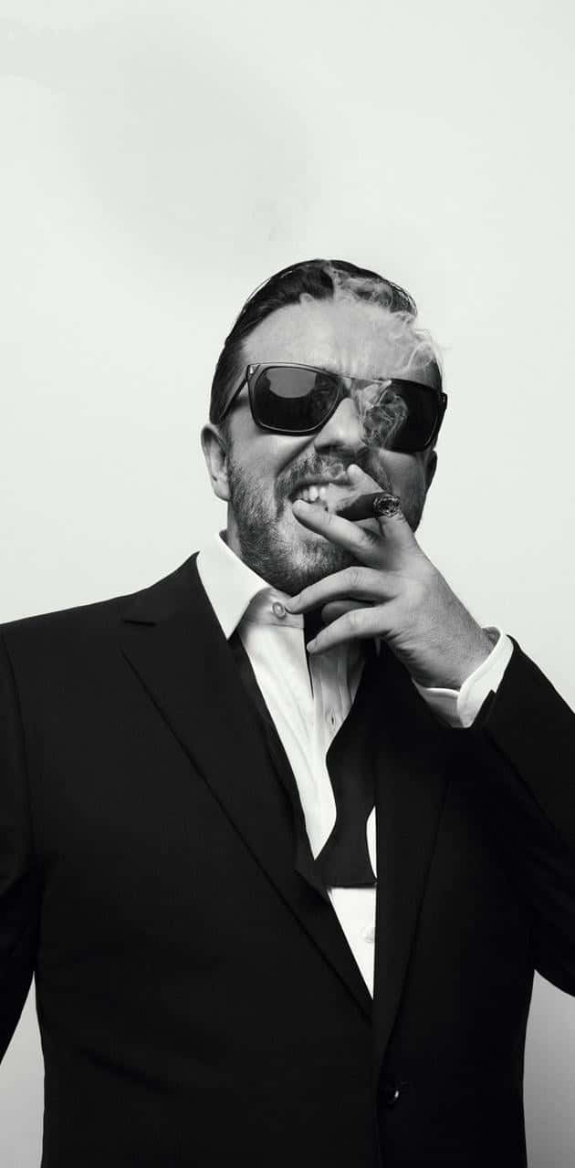 ricky gervais 桌布 壁紙 — 一位穿著黑色西裝和太陽眼鏡的時尚男士，在純白色背景前以單色調抽雪茄。