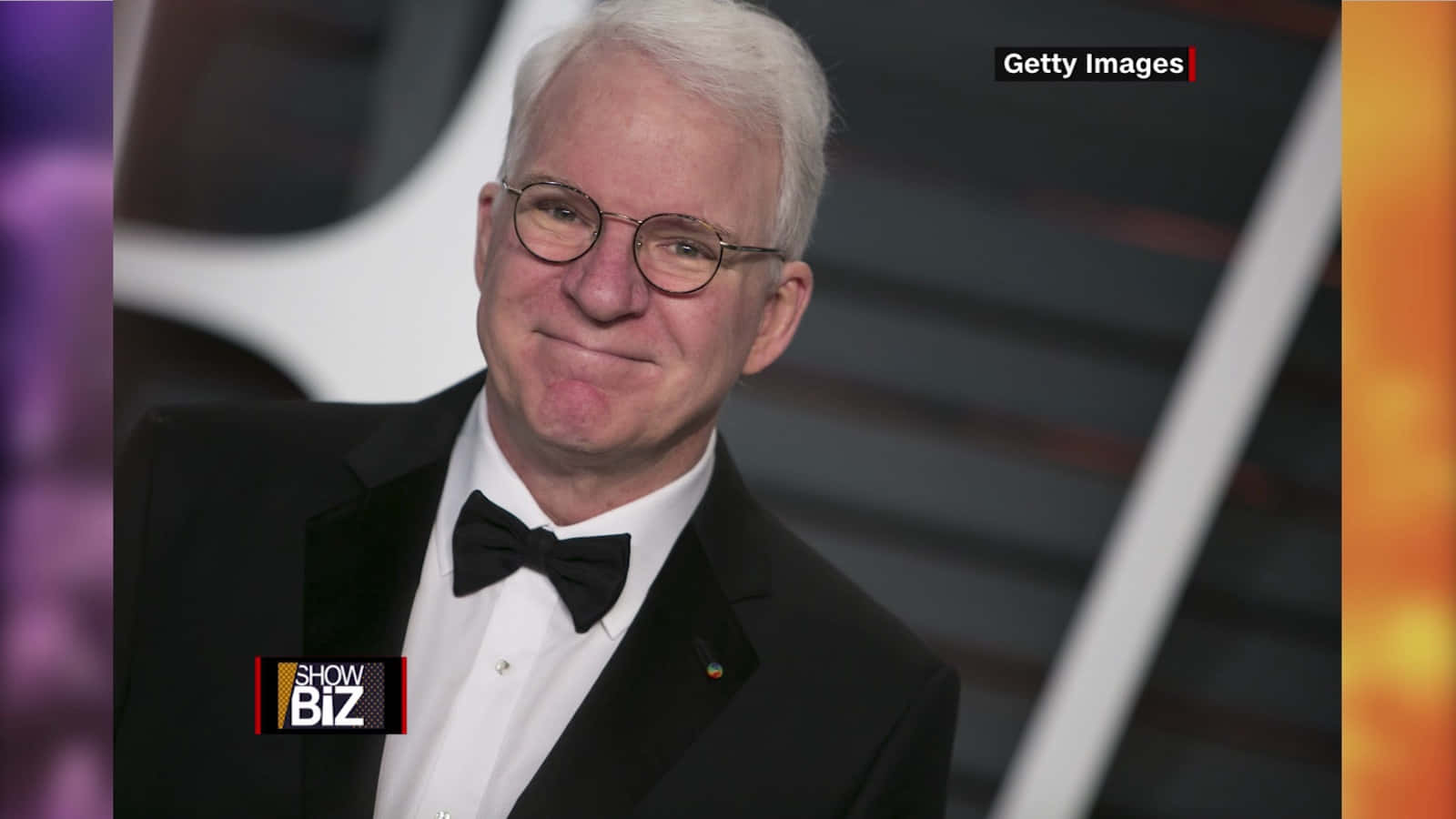steve martin 桌布 壁紙 — 一位笑容滿面、白髮戴眼鏡的男士，在華麗場合穿著黑色燕尾服和領結。