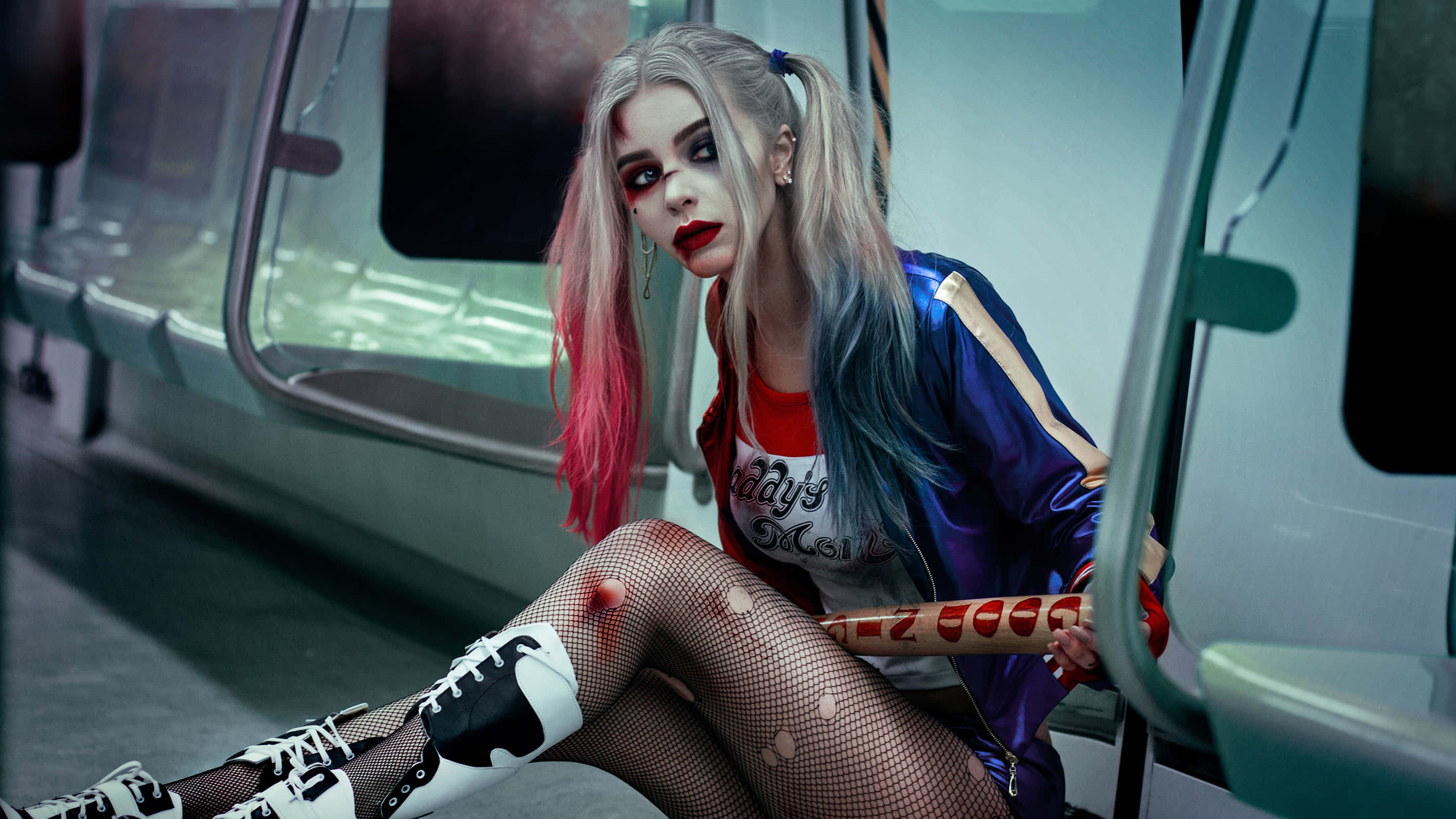 Harley Quinn Cosplay 桌布 壁紙 — 一位粉紅和藍色頭髮的女性坐在地鐵座位上，拿著棒球棍，雙腿血淋淋，穿著漁網襪。
