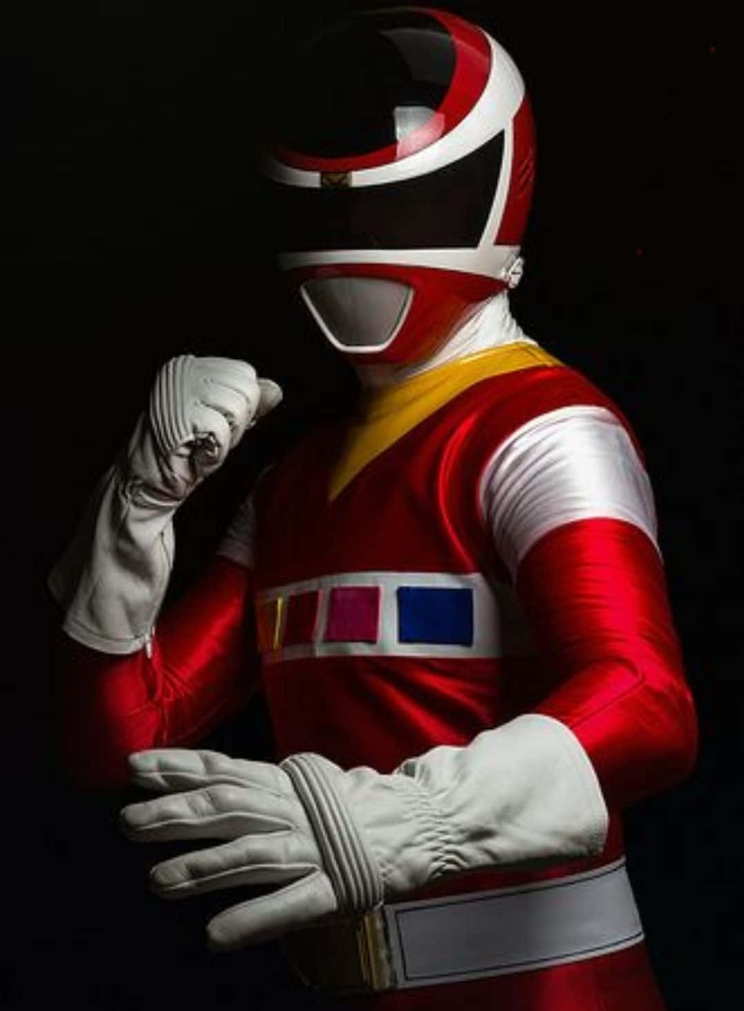 Power Rangers 桌布 壁紙 — 一位紅色戰士穿著全套服裝，在黑色背景前自信地擺出姿勢，一隻拳頭舉起。