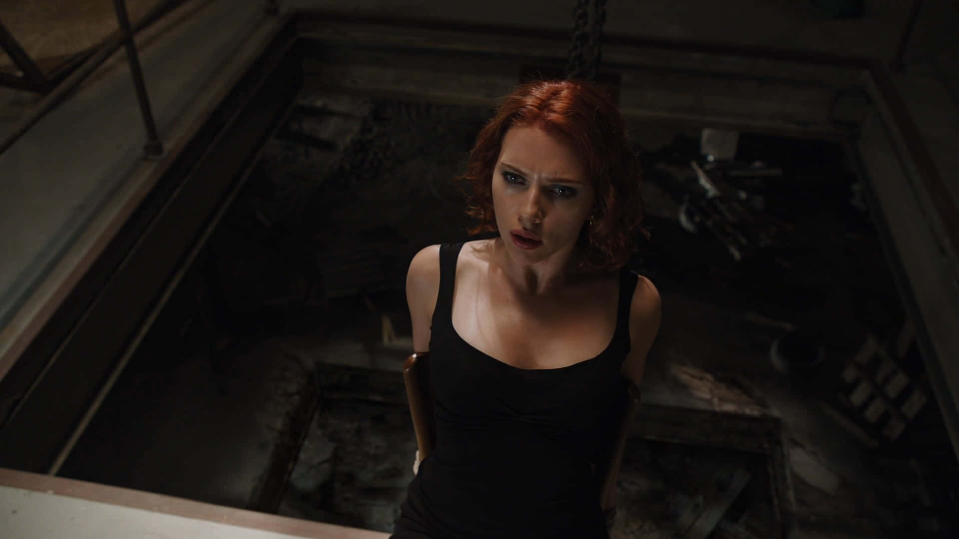 黑寡婦 桌布 壁紙 — 一位紅髮女子身穿黑色背心，從陰暗骯髒的工業環境中向上凝視。