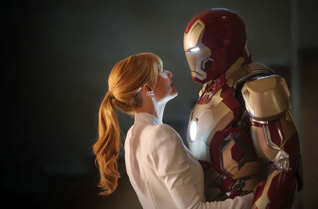 Iron Man Movies 桌布 壁紙 — 一位紅髮女性在昏暗的房間裡仰望鐵甲奇俠，他們的臉龐在親密時刻中靠近。
