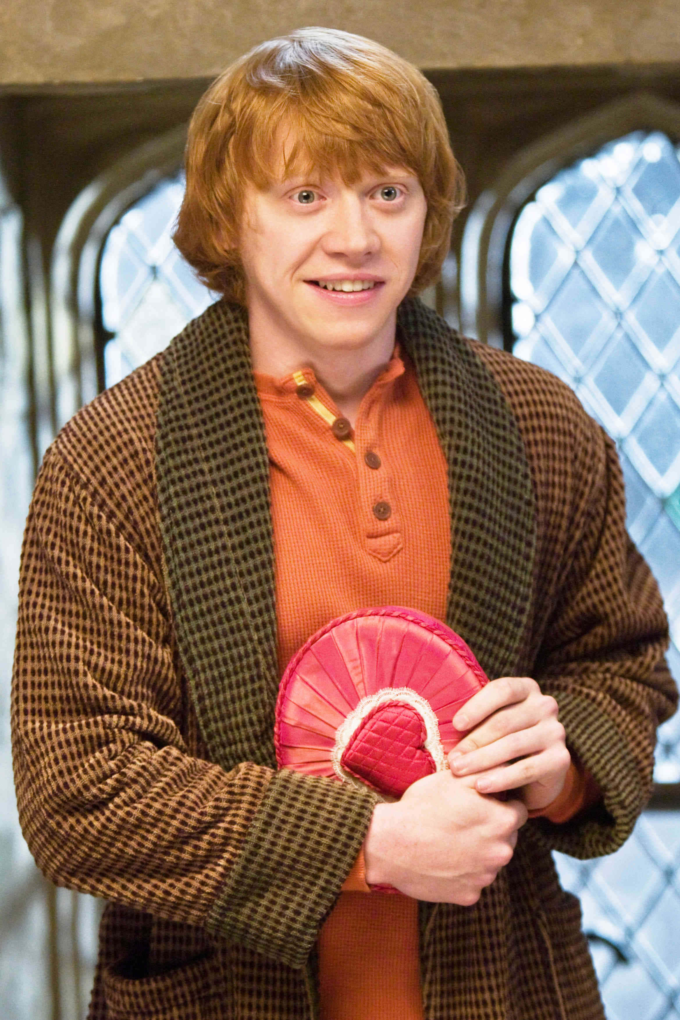The Half-blood Prince 桌布 壁紙 — 一位紅髮年輕男子穿著格紋長袍，手持粉紅色心形物體，表情驚訝。