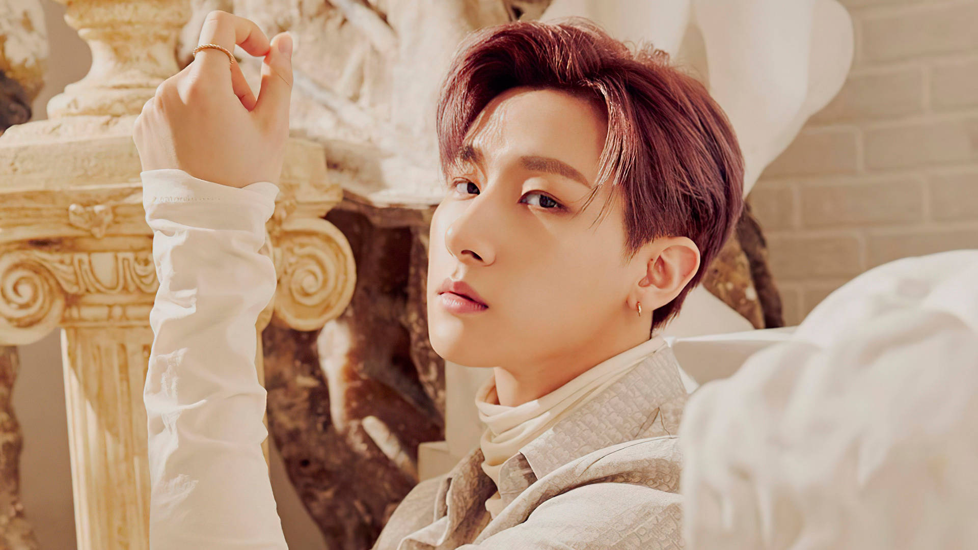 Monsta X IM Fantasia X 壁紙 — 一位紅髮年輕男子身穿白色服裝，在溫暖的金色光線下，優雅地站在華麗的古典柱子旁。