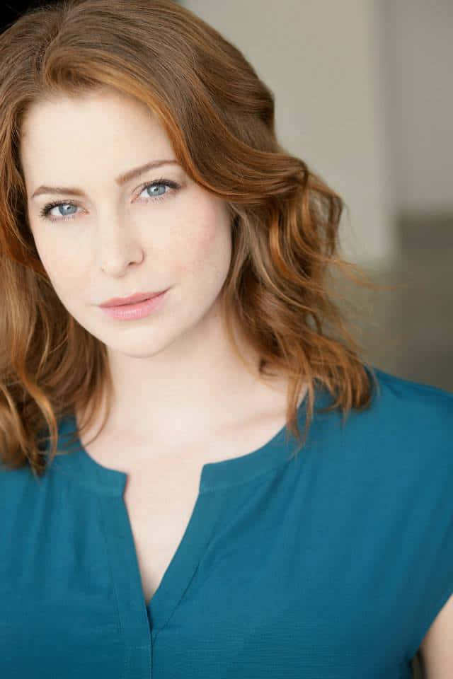Esmé Bianco 桌布 壁紙 — 一位紅髮藍眼的女性，在柔和燈光的攝影棚肖像中穿著青綠色上衣。