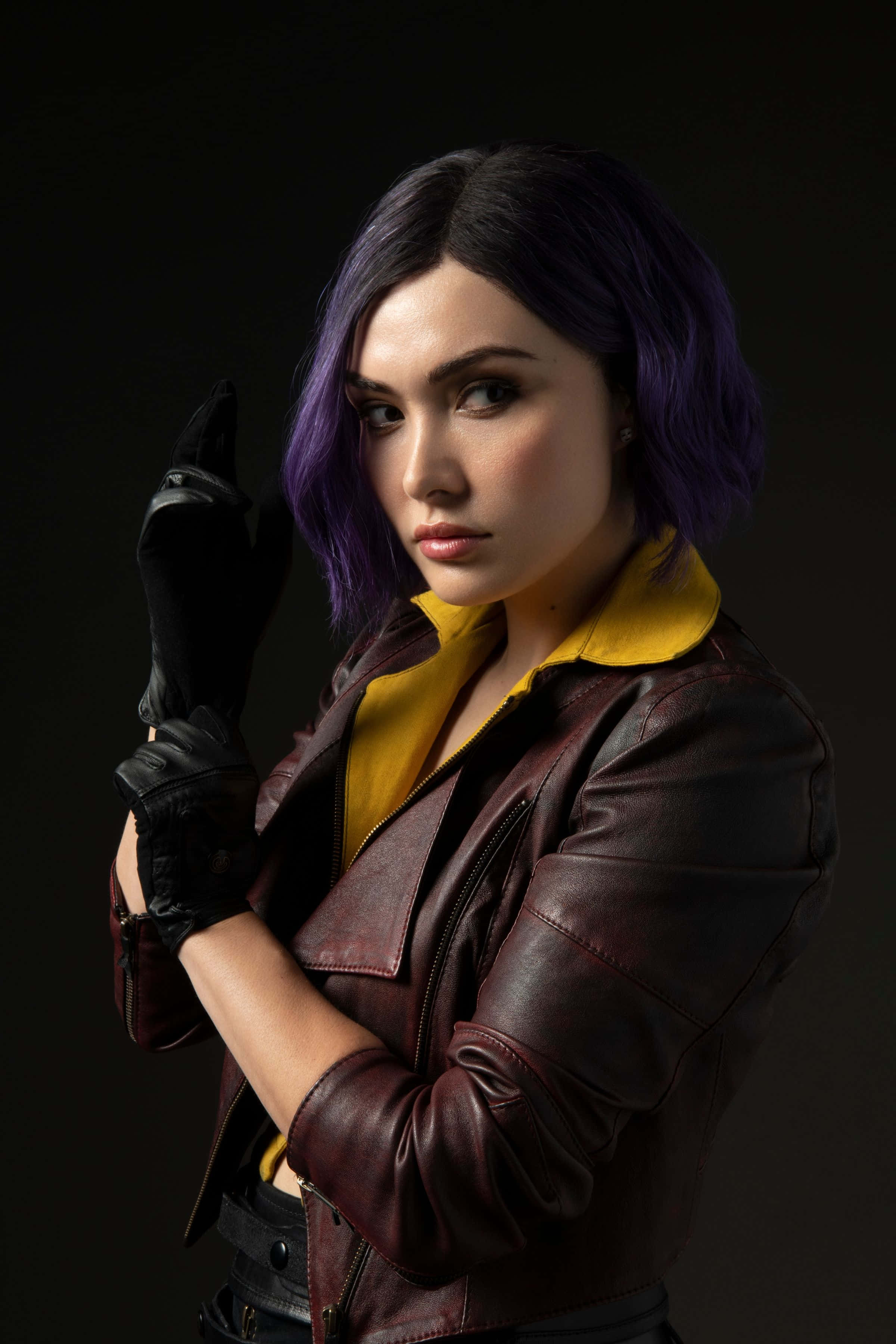 Faye Valentine 桌布 壁紙 — 一位紫色頭髮的女性，在深色背景前穿著一件黃色領的棕色皮褸和黑色手套。