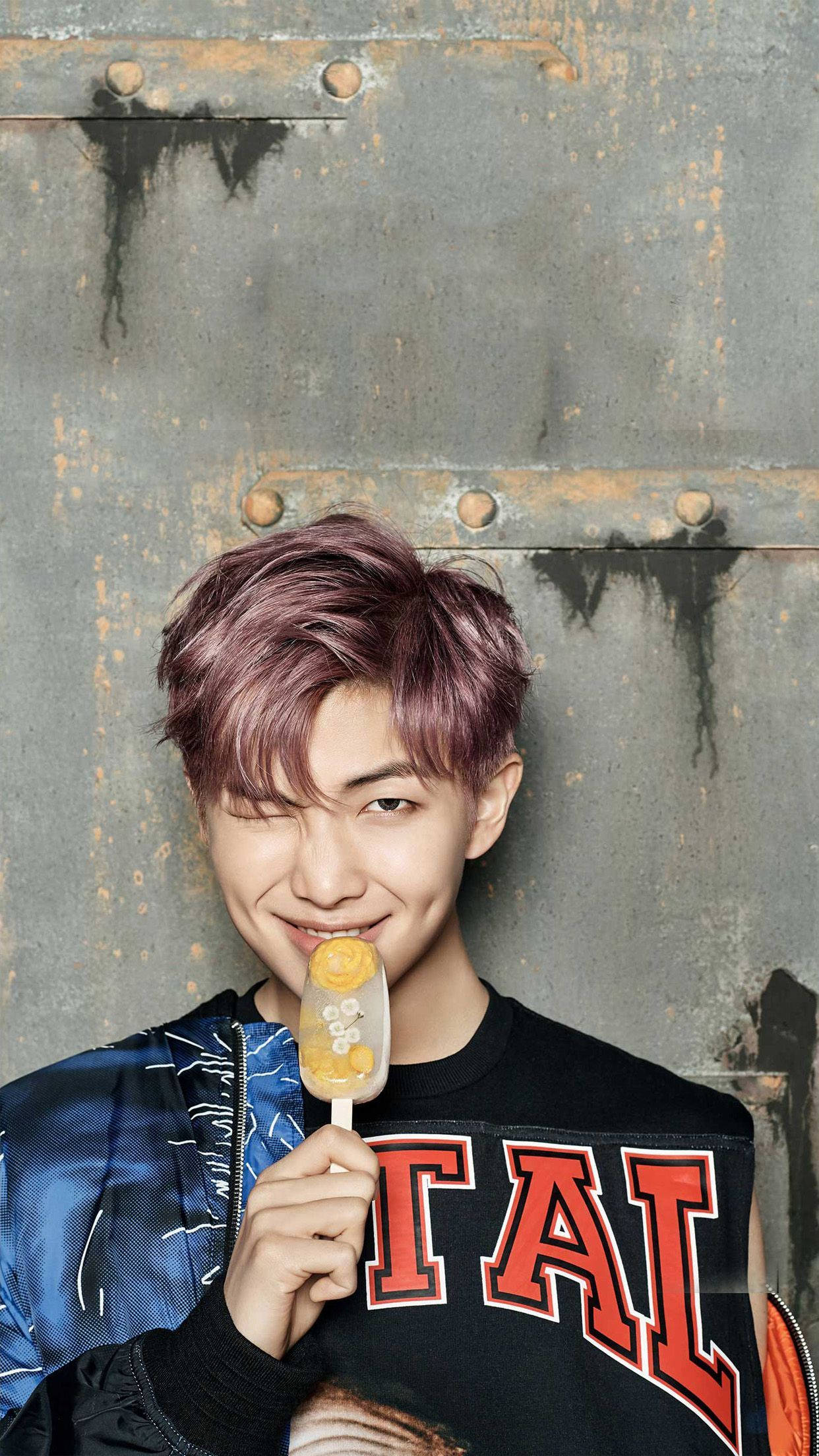 RM BTS《Spring Day》2017 壁紙 — 一位紫髮年輕男子微笑著，將冰棒靠在生鏽的金屬牆上。